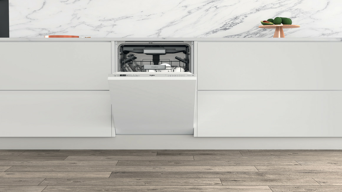 Una lavastoviglie bianca è integrata nei moderni mobili da cucina sotto un piano di lavoro in marmo.