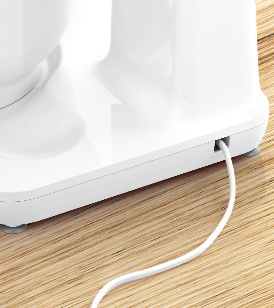 Un cavo di alimentazione bianco fuoriesce dal retro di un elettrodomestico da cucina bianco su una superficie di legno.