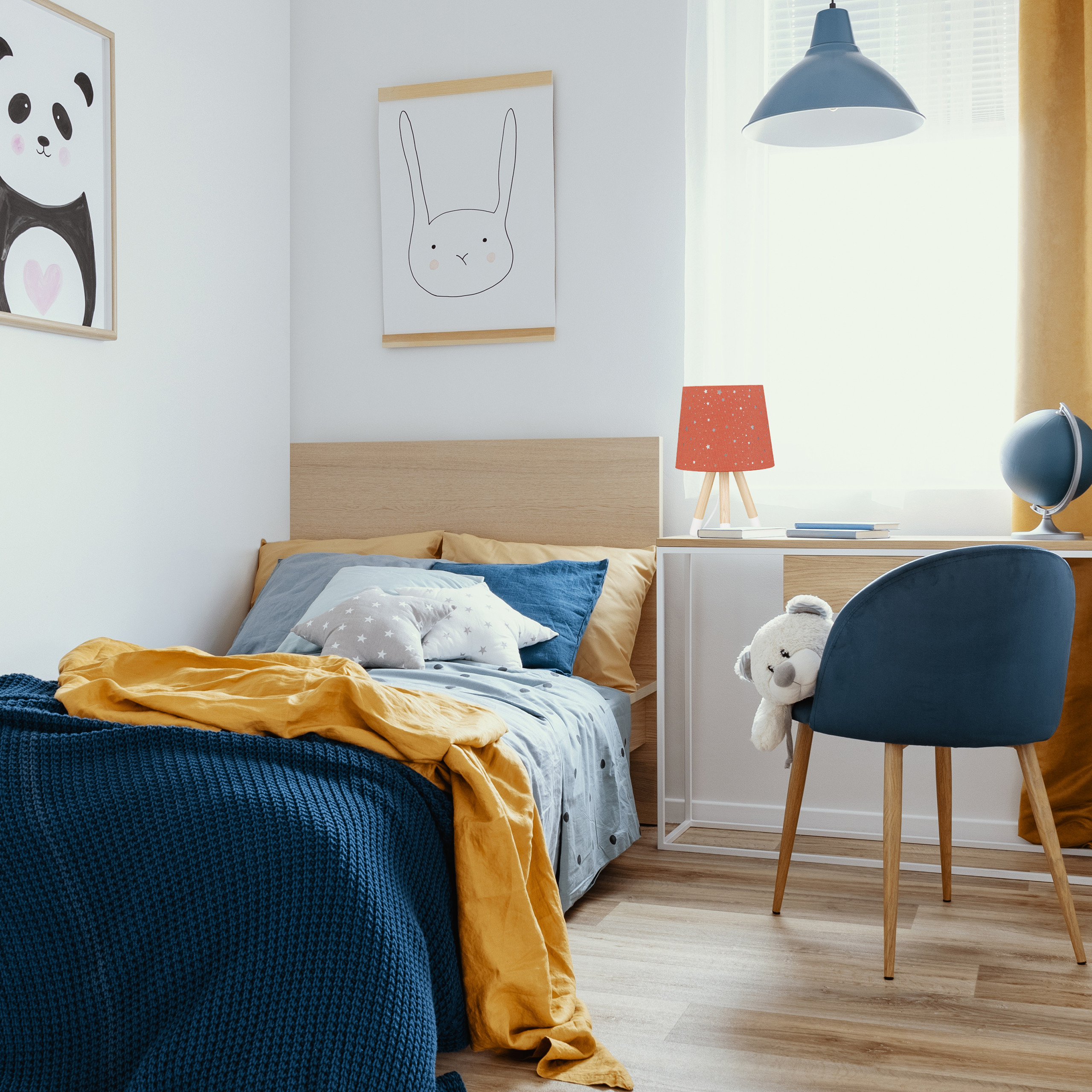 Ein Kinderzimmer mit einem Bett mit blauen und gelben Decken, Tierwandkunst und einem blauen Schreibtischstuhl.
