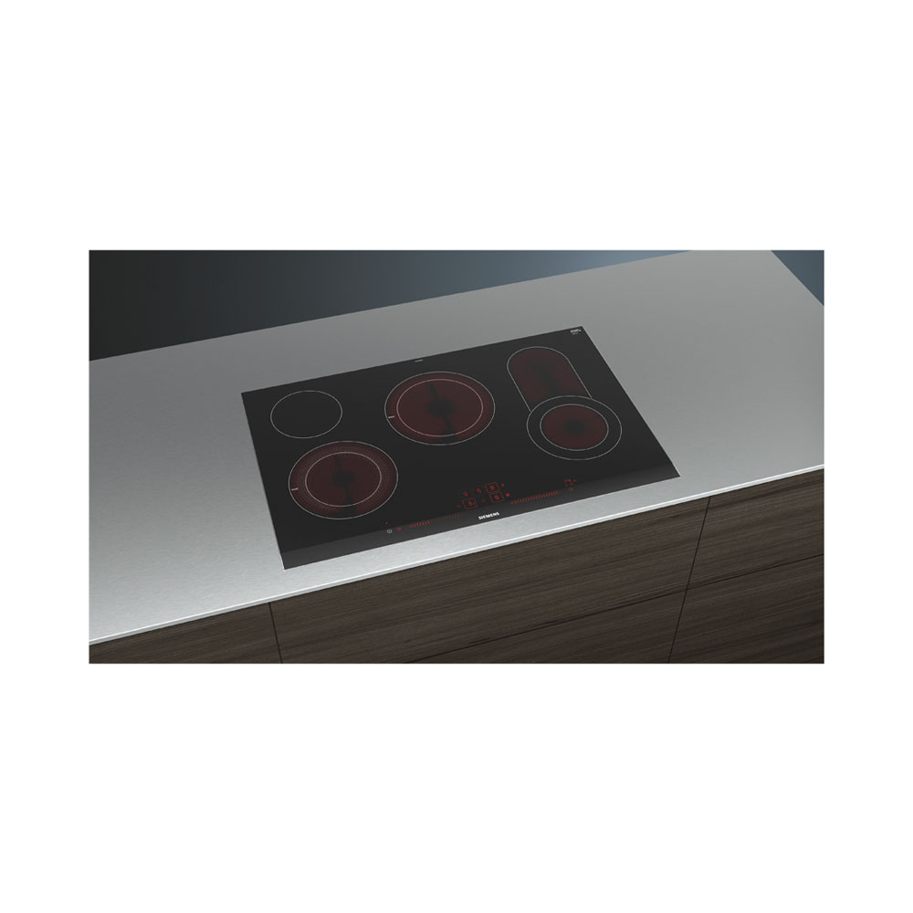 Une table de cuisson à induction noire avec des zones de chauffe rouges est encastrée dans un plan de travail clair.