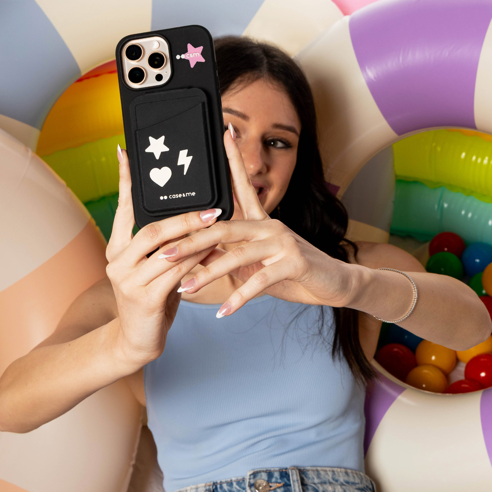 Una mujer con top azul se hace un selfi frente a un fondo colorido.