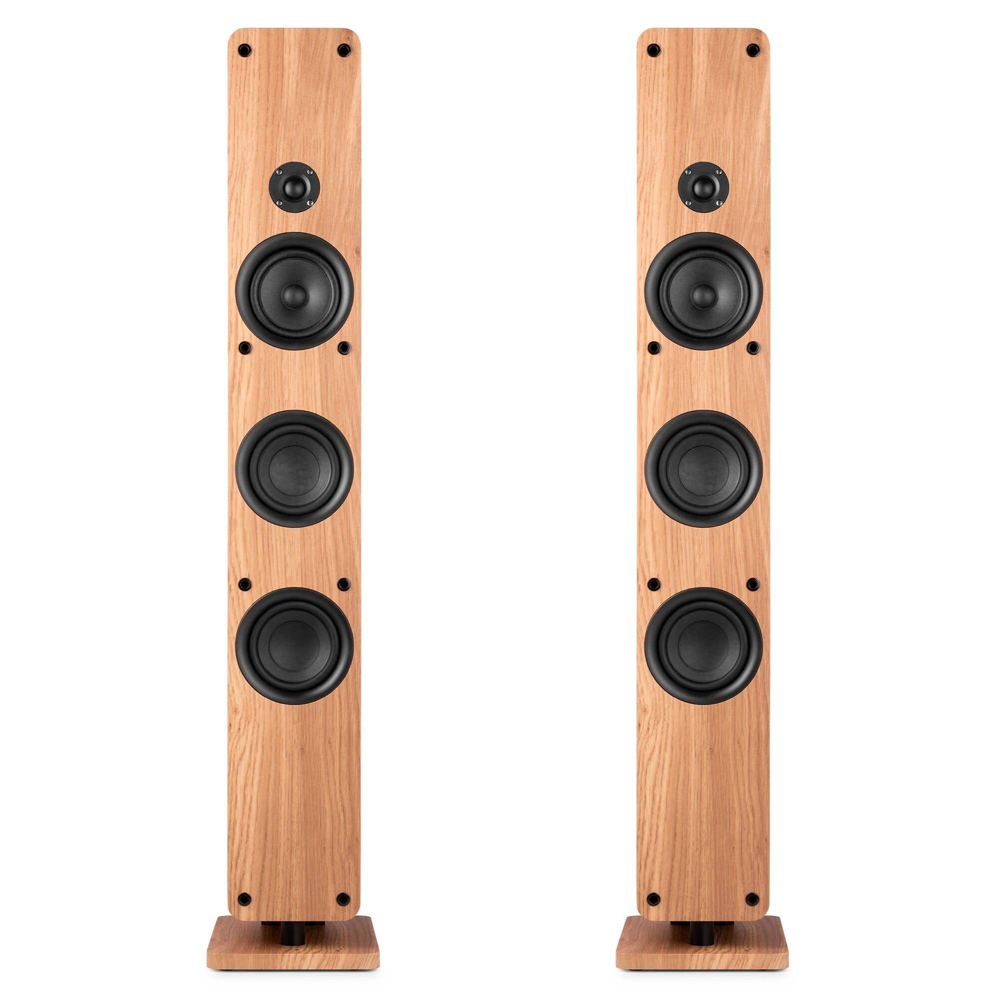 Dos altavoces de suelo de madera clara, altos, con controladores negros y bases rectangulares sobre fondo blanco.