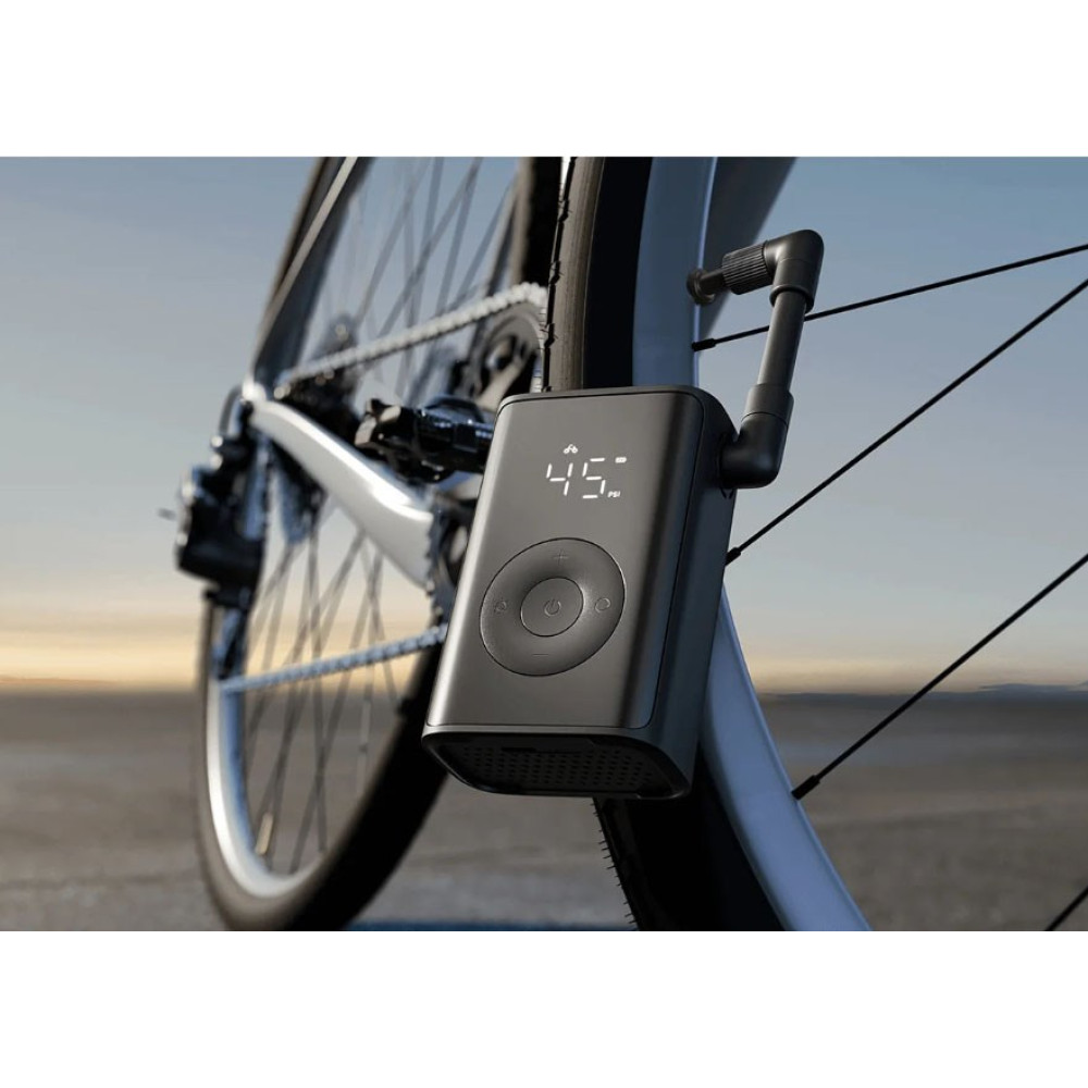 Una pompa d'aria elettrica nera montata su una gomma da bici, con cielo sereno sullo sfondo.