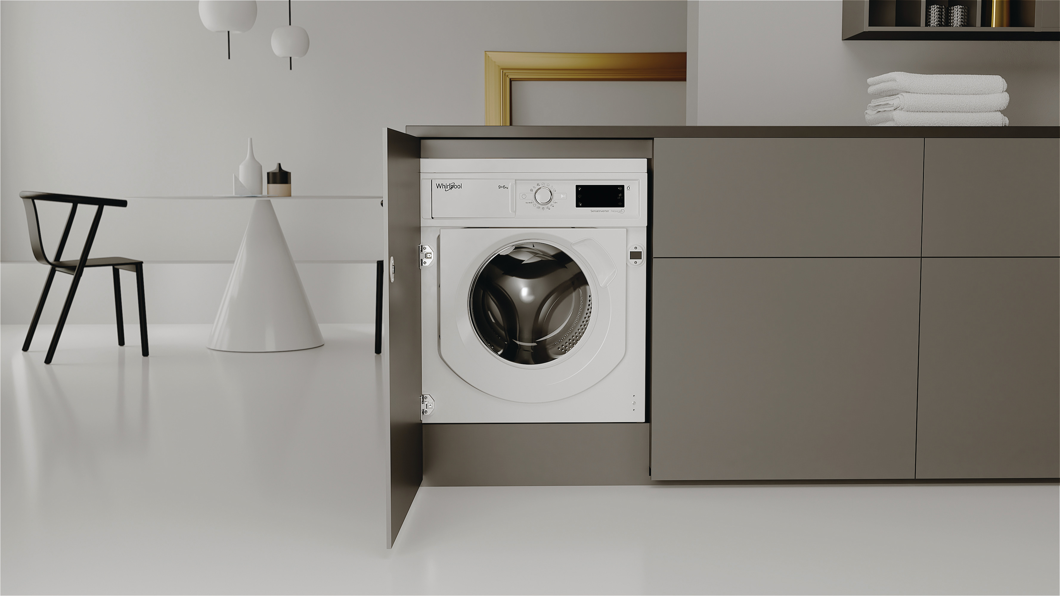 Una lavatrice bianca Whirlpool è integrata in un mobile da cucina grigio, con un tavolo e una sedia sullo sfondo.