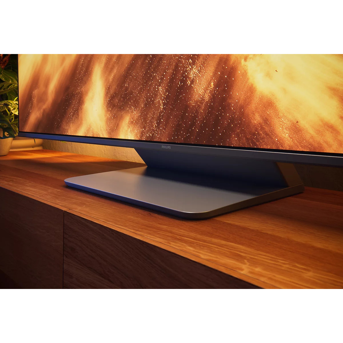 Un televisore Philips che mostra un'immagine di fuoco poggia su un mobile in legno.