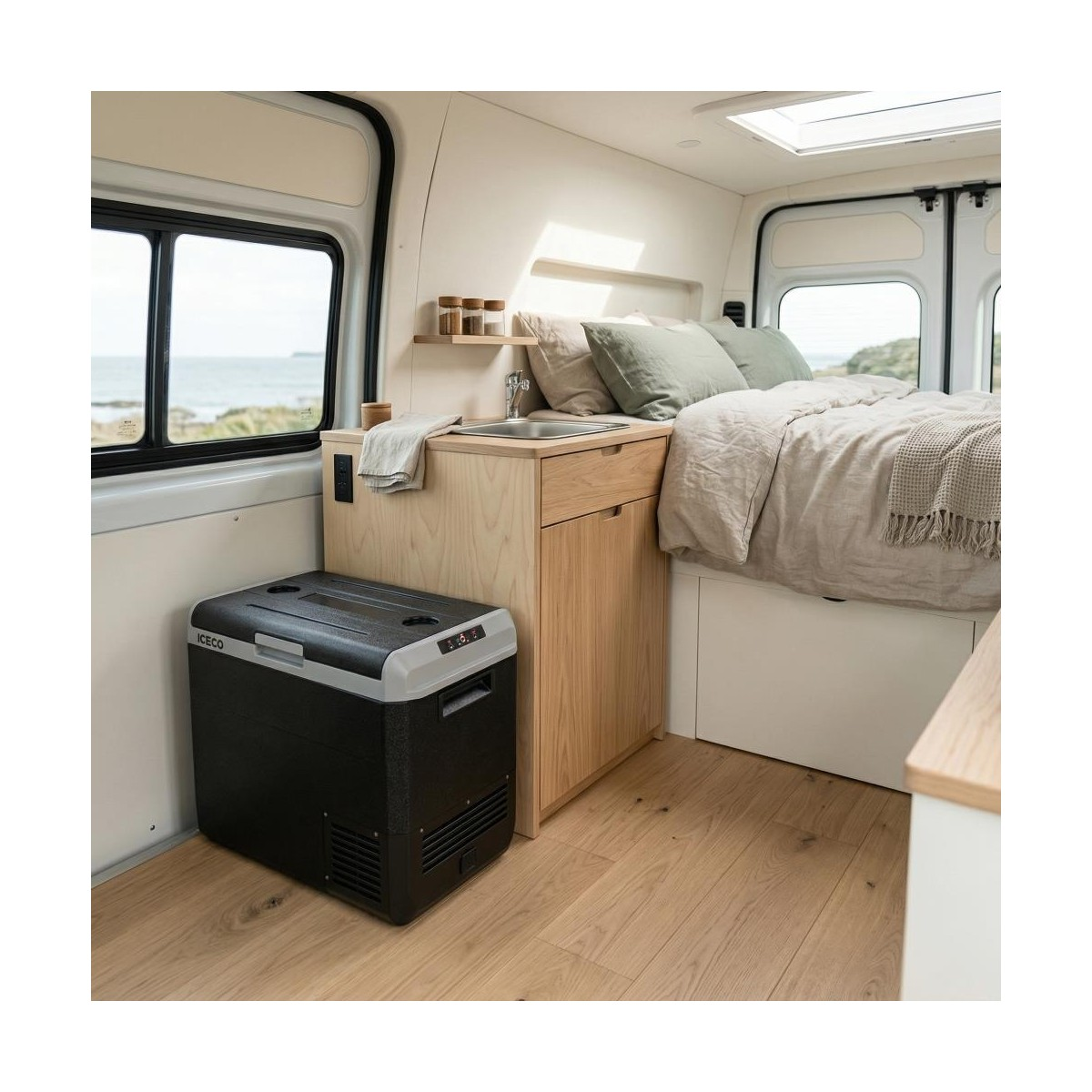 Ahşap zeminli, küçük mutfaklı, yataklı ve taşınabilir buzdolaplı modern karavan içi.