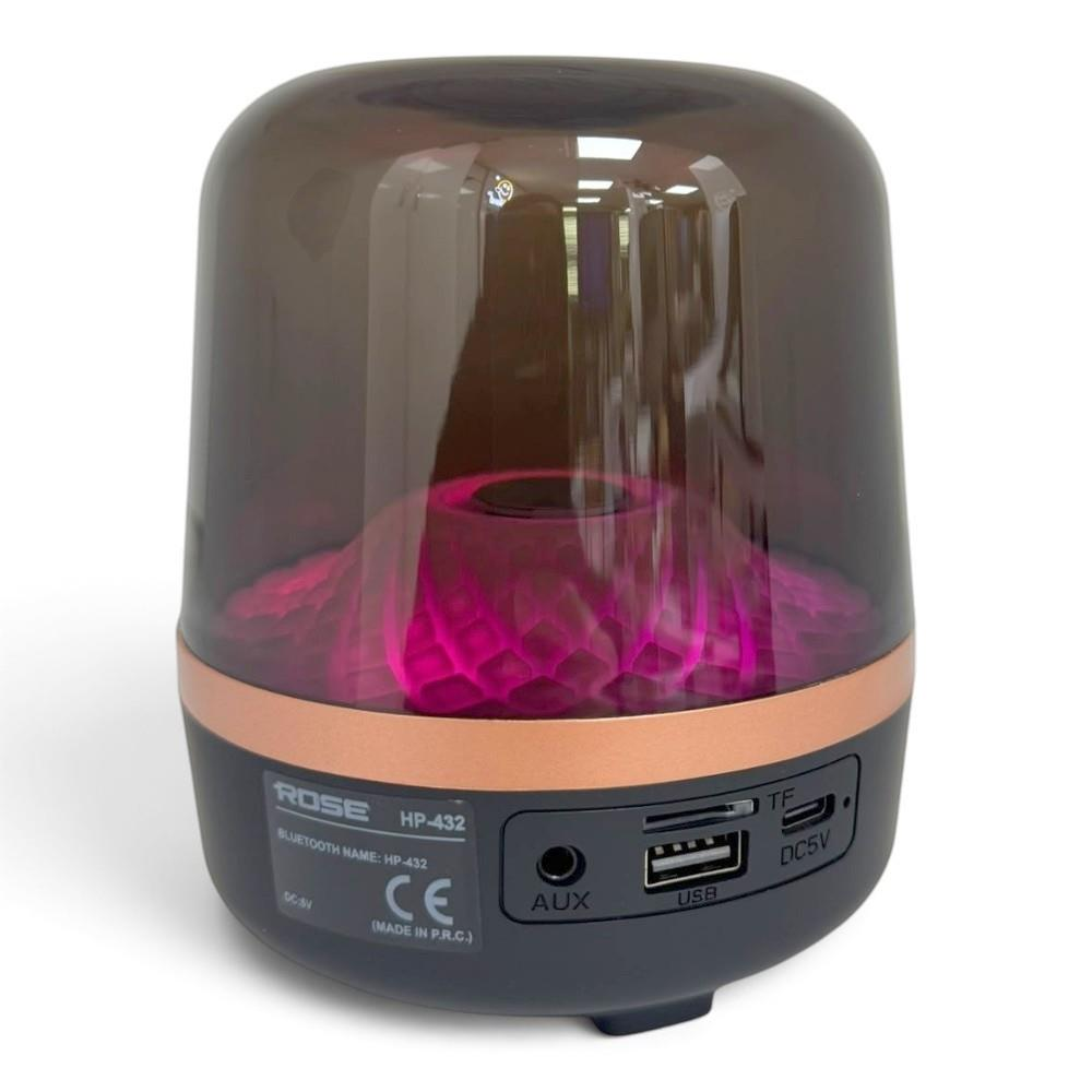 Renkli camlı, pembe altın şeritli ve pembe iç aydınlatmalı silindirik bir Bluetooth hoparlör.