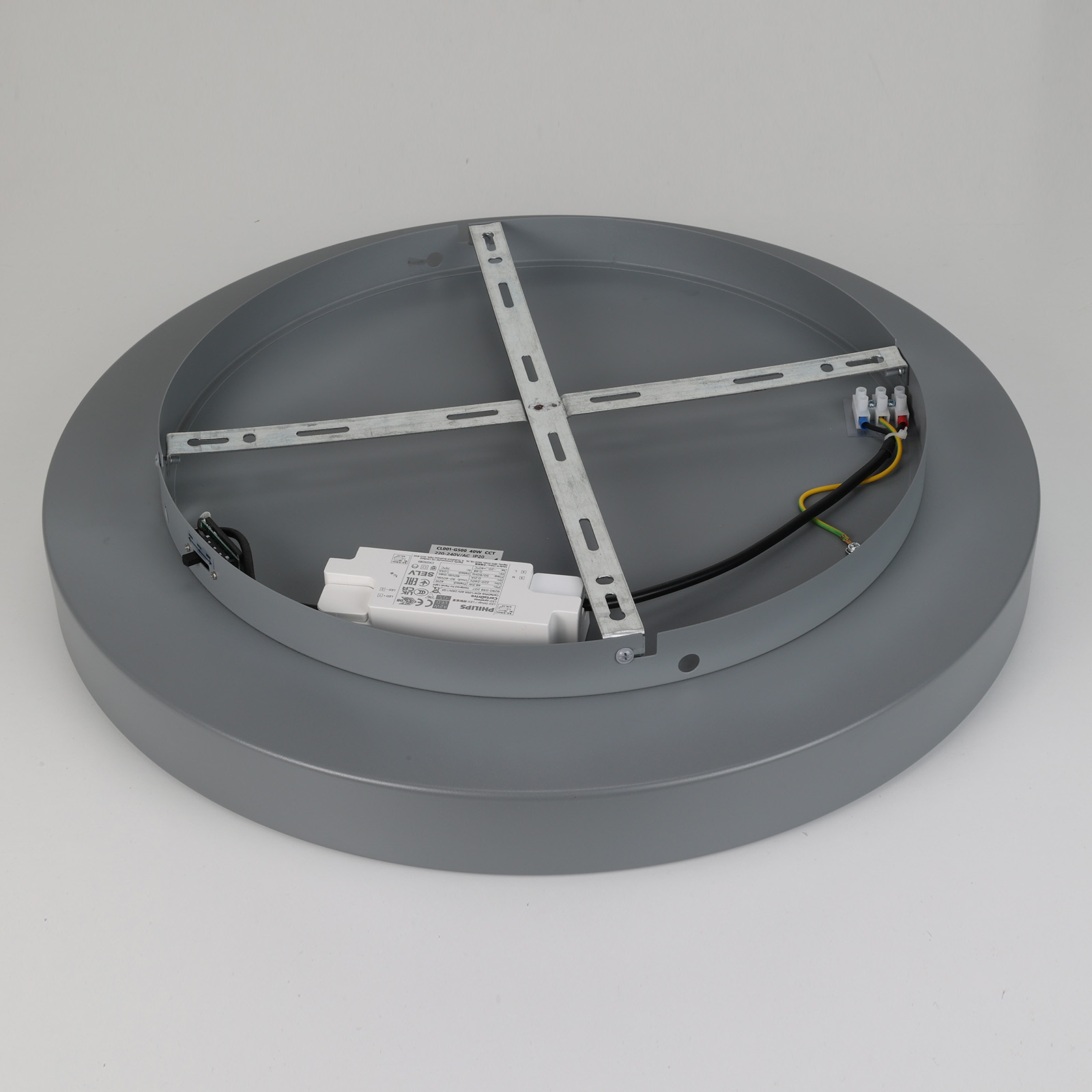 Parte trasera de una lámpara de techo gris con marco metálico interno, balasto blanco y cables eléctricos.