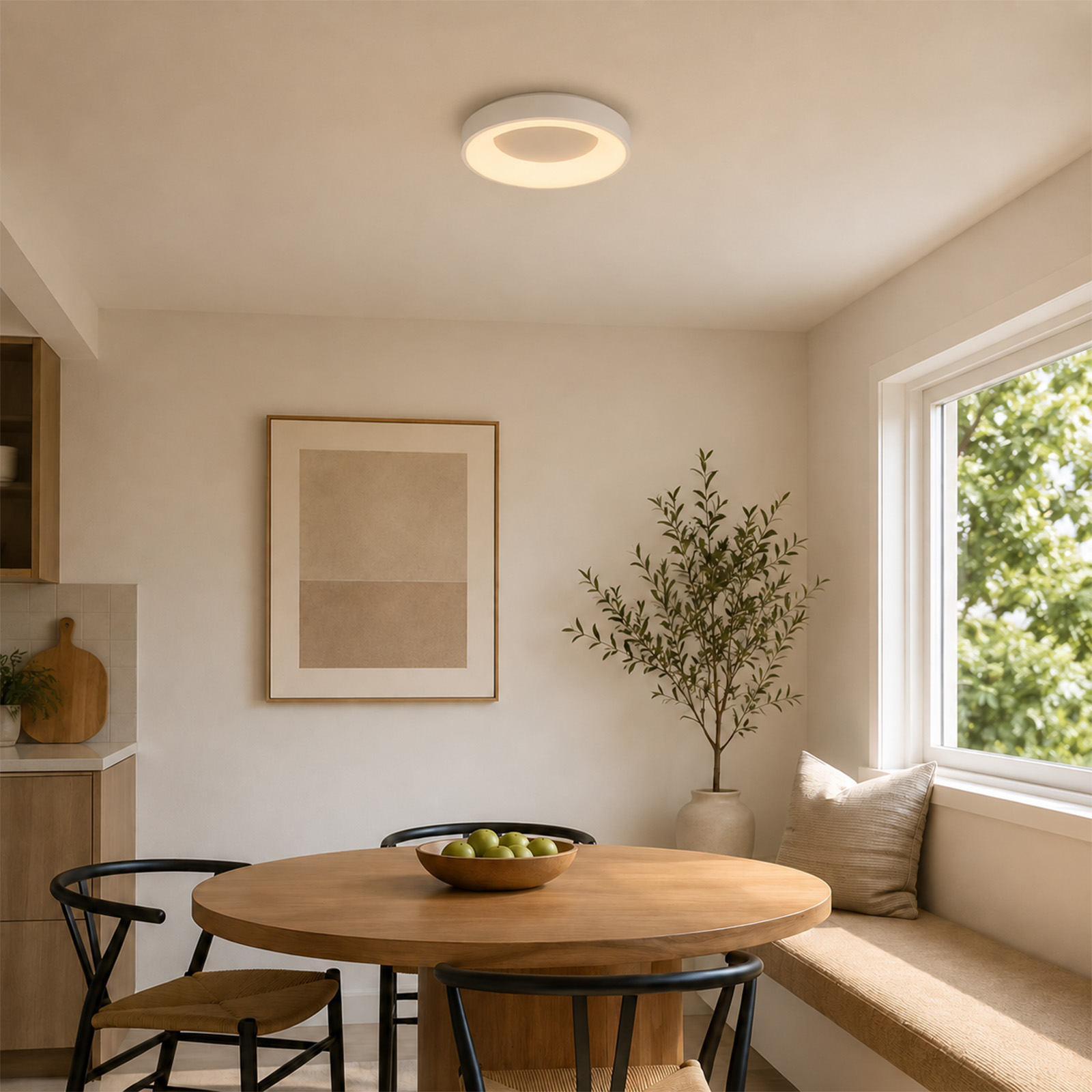 Comedor acogedor con mesa redonda de madera, sillas, cuadro, planta y una luz de techo LED redonda.