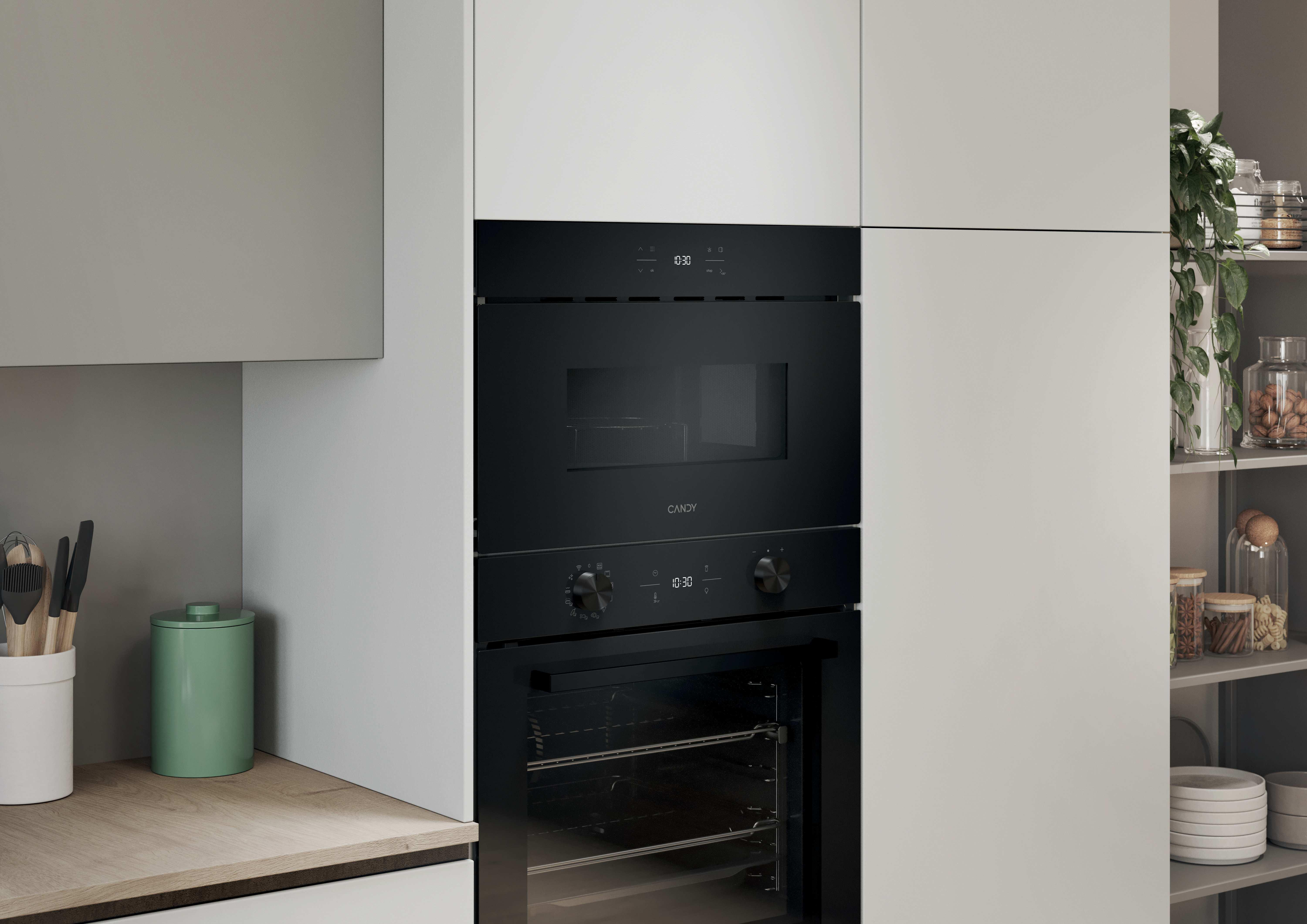 Moderno forno a microonde e forno da incasso neri in una cucina luminosa con piano di lavoro in legno e ripiani.