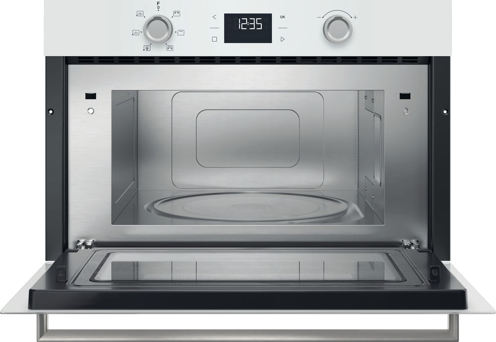 Un forno a microonde bianco con la porta aperta, interno in acciaio inox e piatto in vetro.