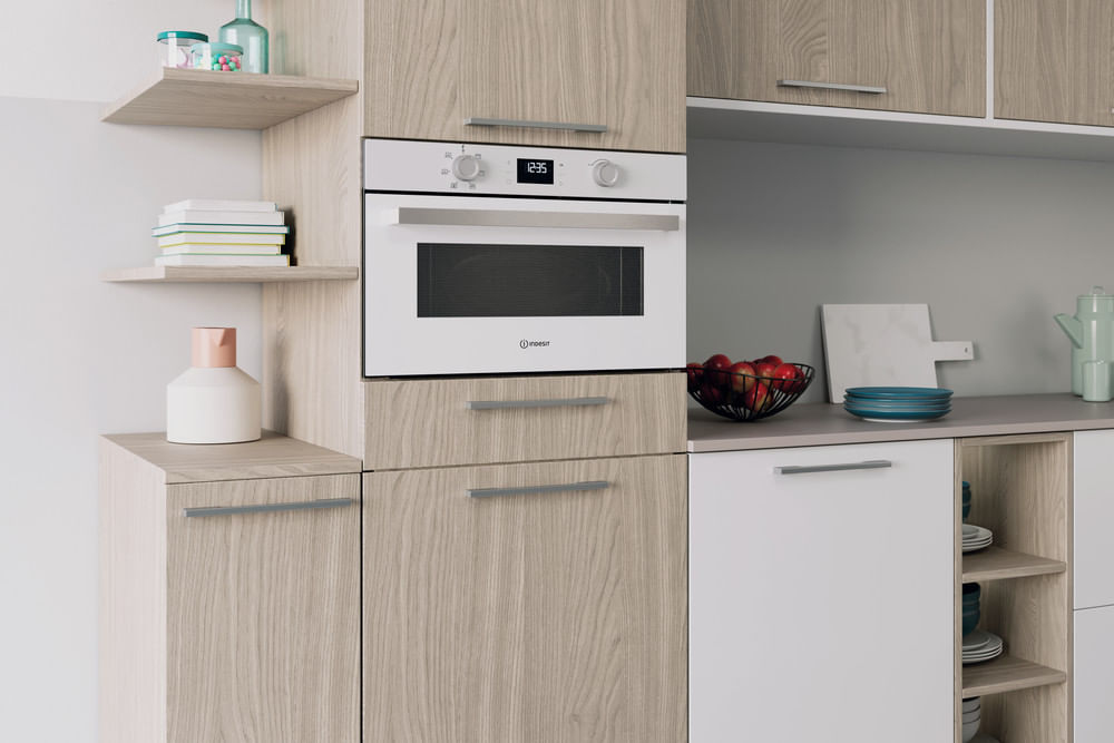 Moderna cucina in legno con forno bianco, mensole, portafrutta e mobili minimalisti.