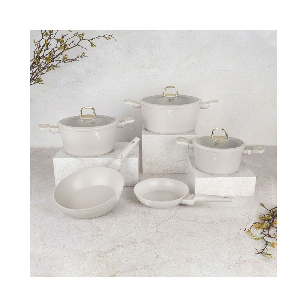 Un ensemble de cinq ustensiles de cuisine beige clair avec couvercles en verre et poêles.