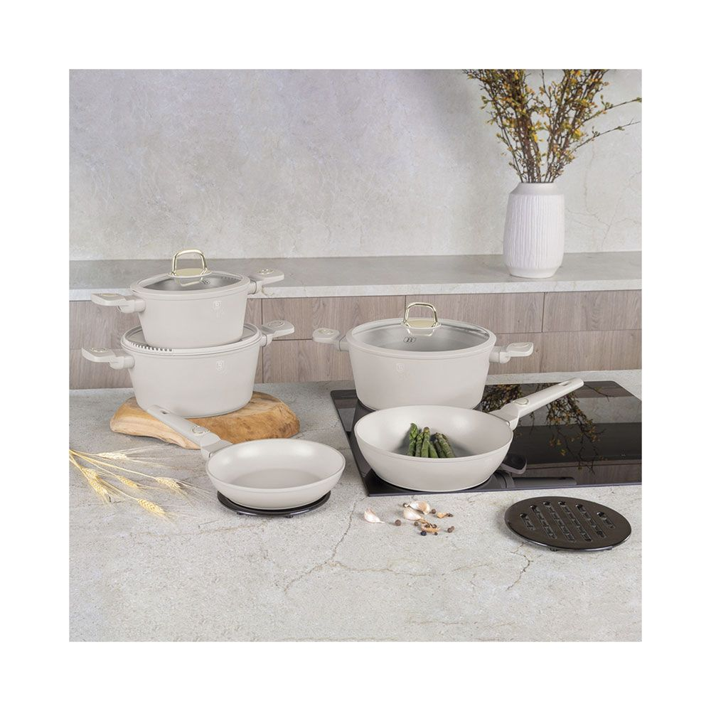 Ensemble de casseroles et poêles couleur crème sur un comptoir de cuisine avec un vase en arrière-plan.