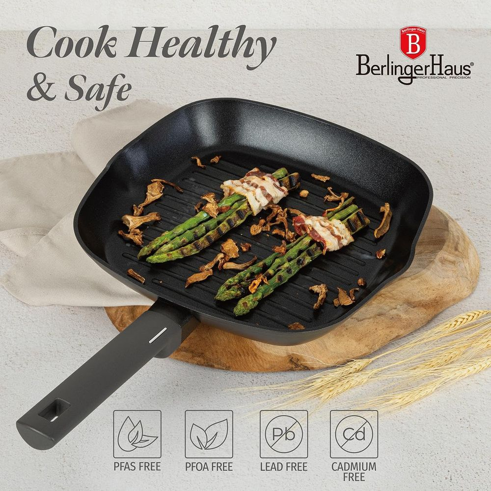 Eine schwarze Grillpfanne auf einem Holzbrett enthält speckumwickelten Spargel und Pilze.