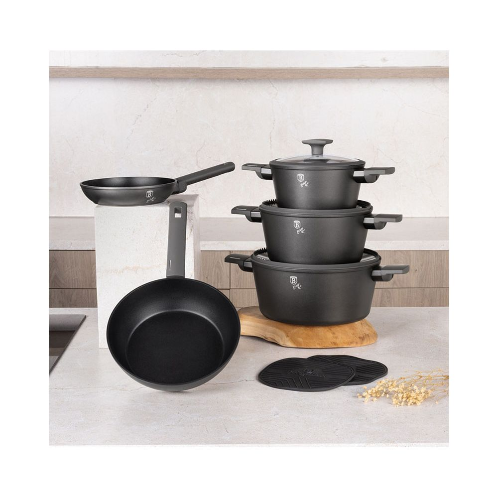 Un ensemble de batterie de cuisine noire comprenant casseroles, poêles et tapis.