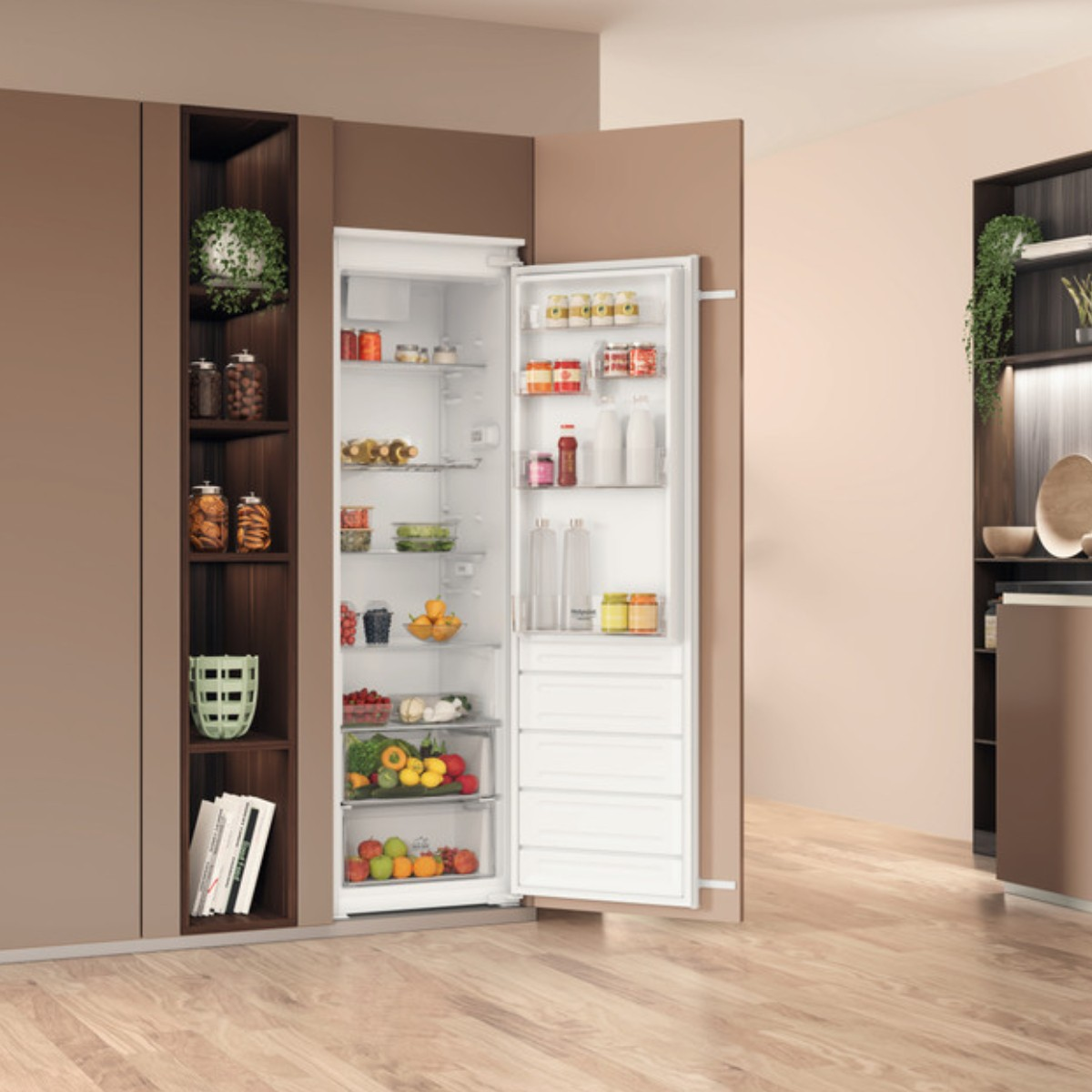 Un frigorifero bianco aperto in una cucina moderna, pieno di cibo, frutta e bottiglie, vicino a mobili in legno.