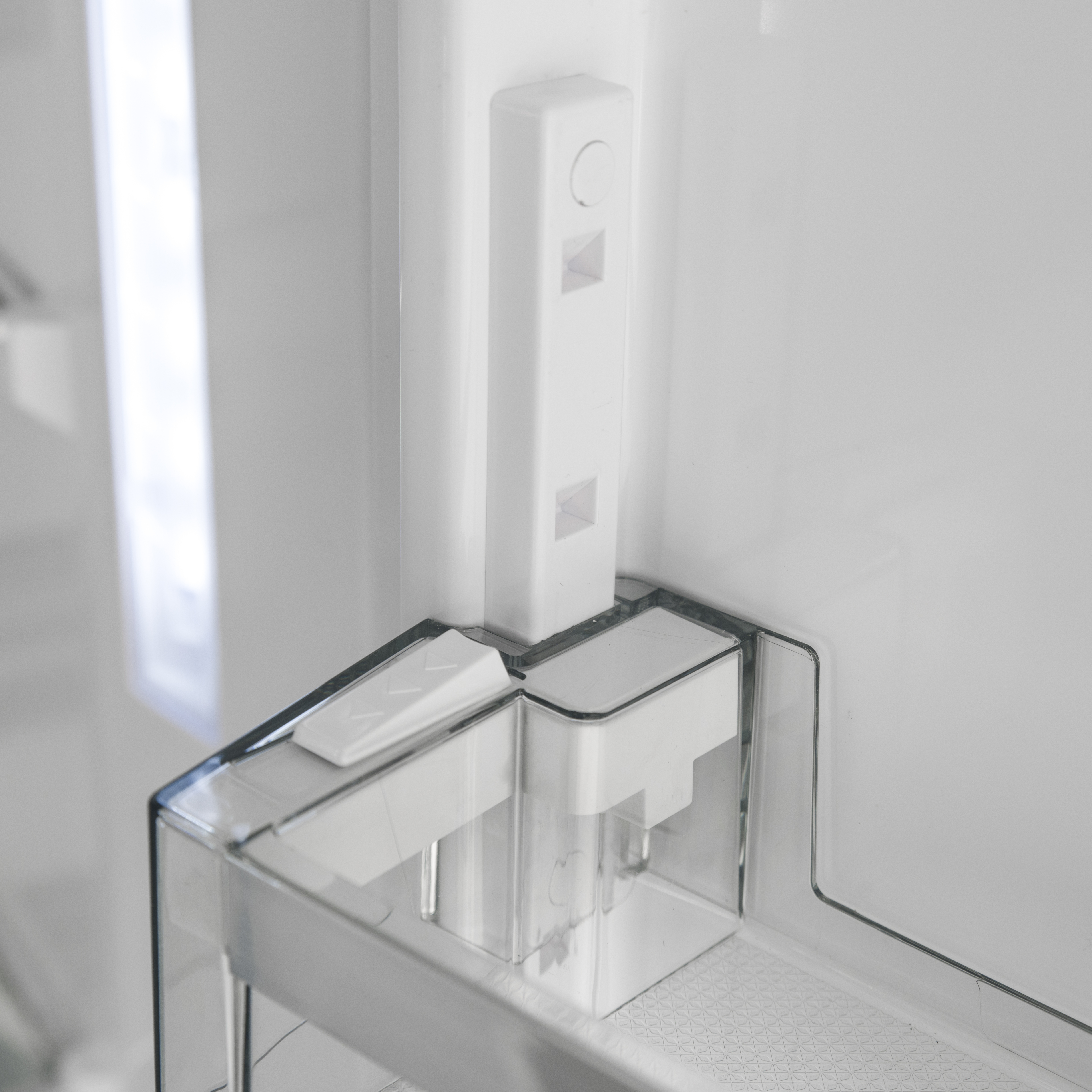 L'interno di un frigorifero bianco con un ripiano della porta trasparente e una guida verticale.