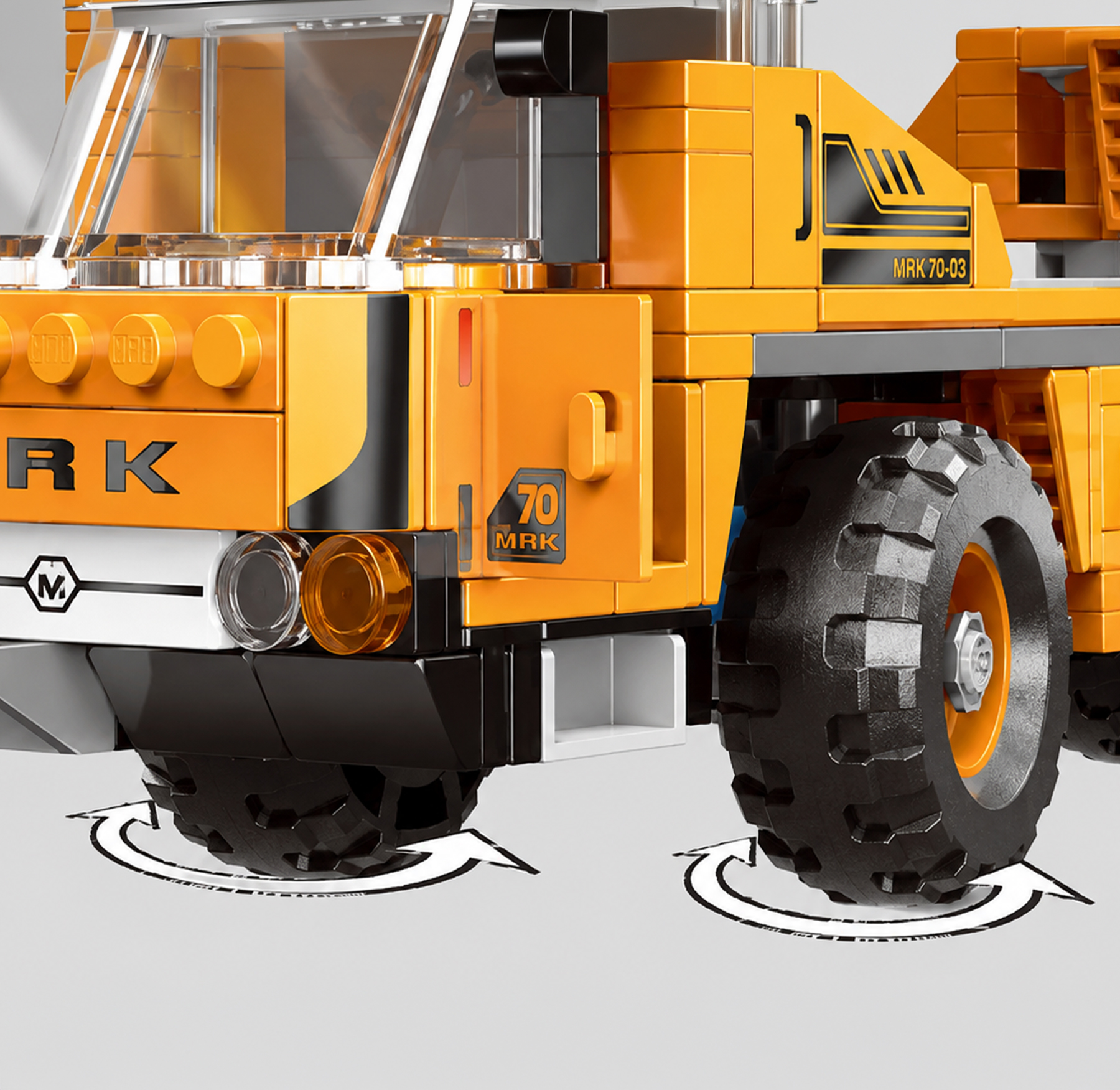 Zbliżenie pomarańczowej ciężarówki Lego z dużymi czarnymi oponami i strzałkami.
