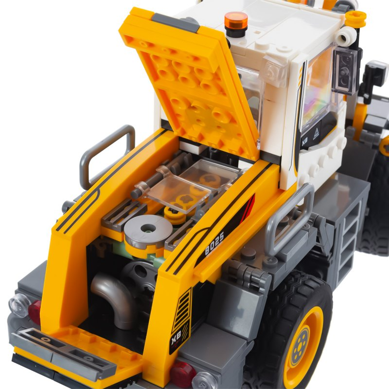 Żółto-biały traktor-zabawka z otwartą maską odsłaniającą szczegółowy silnik.