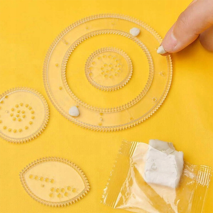 Palec umieszcza białą glinkę na przezroczystej plastikowej układance zębatkowej na żółtym tle.