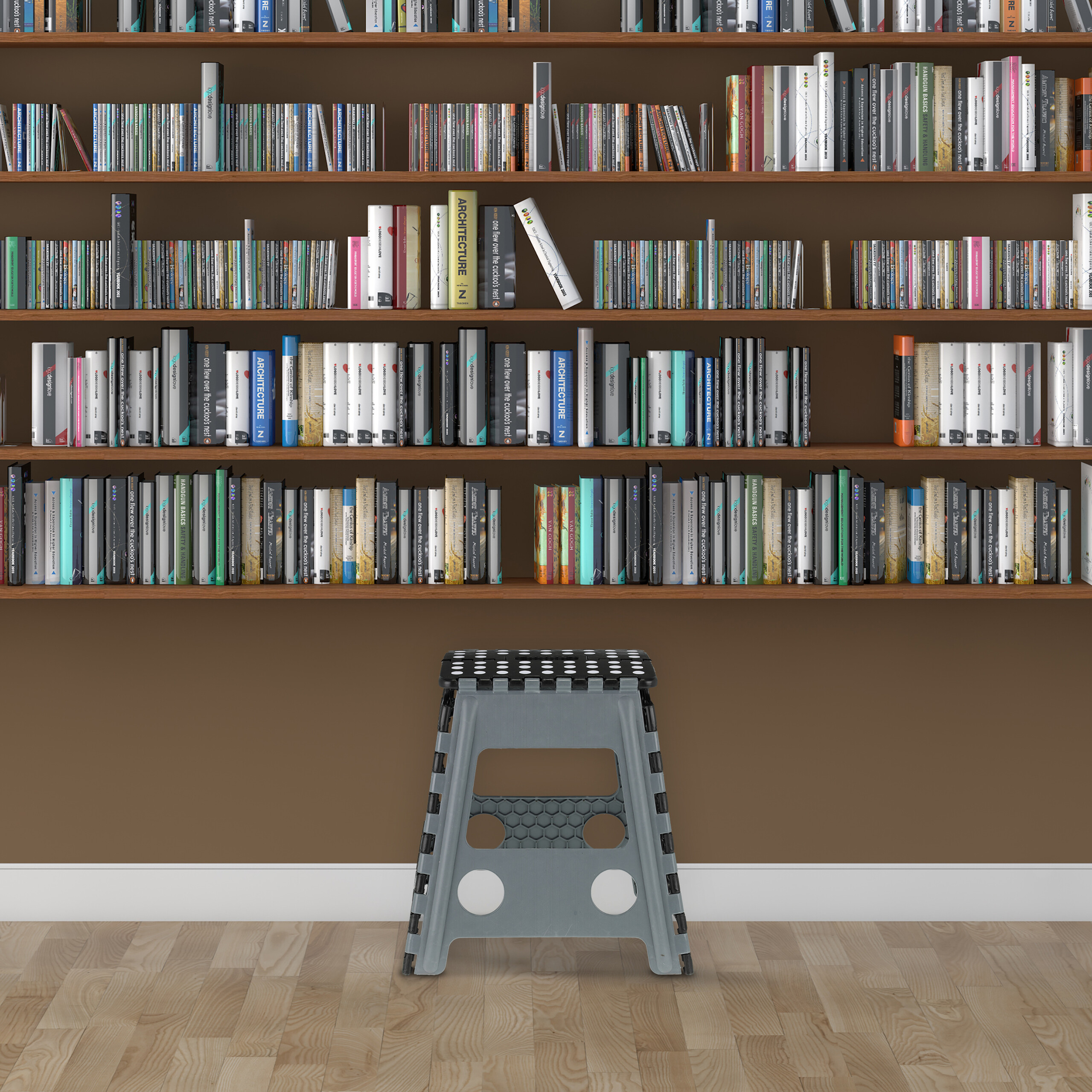 Ein grauer Klapptritt steht auf einem Holzboden vor hohen, bunten Bücherregalen.