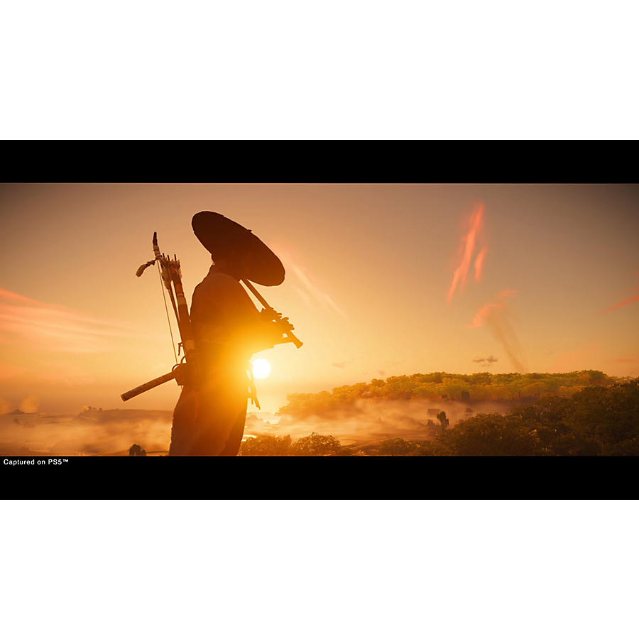 Silhouette d'une personne en vêtements traditionnels et chapeau au coucher du soleil devant un paysage boisé.