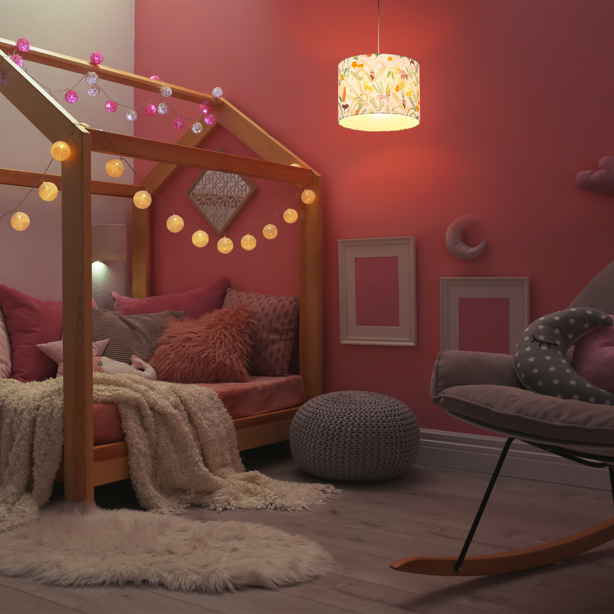 Gemütliches Kinderzimmer in Rosa mit Holzbett, Lichterkette, Schaukelstuhl und pastellfarbener Deckenleuchte.