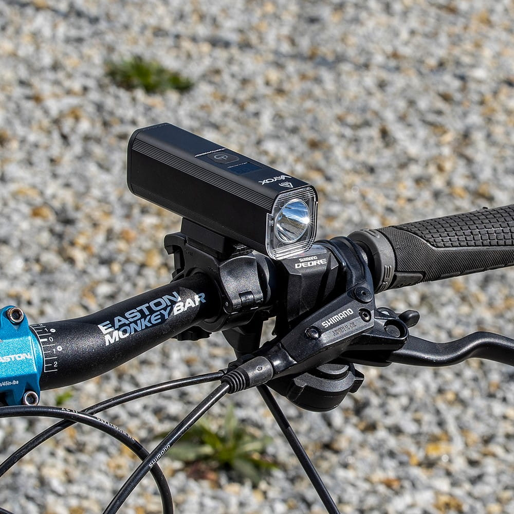 Czarna lampka rowerowa zamontowana na kierownicy Easton Monkey Bar z hamulcami Shimano Deore.