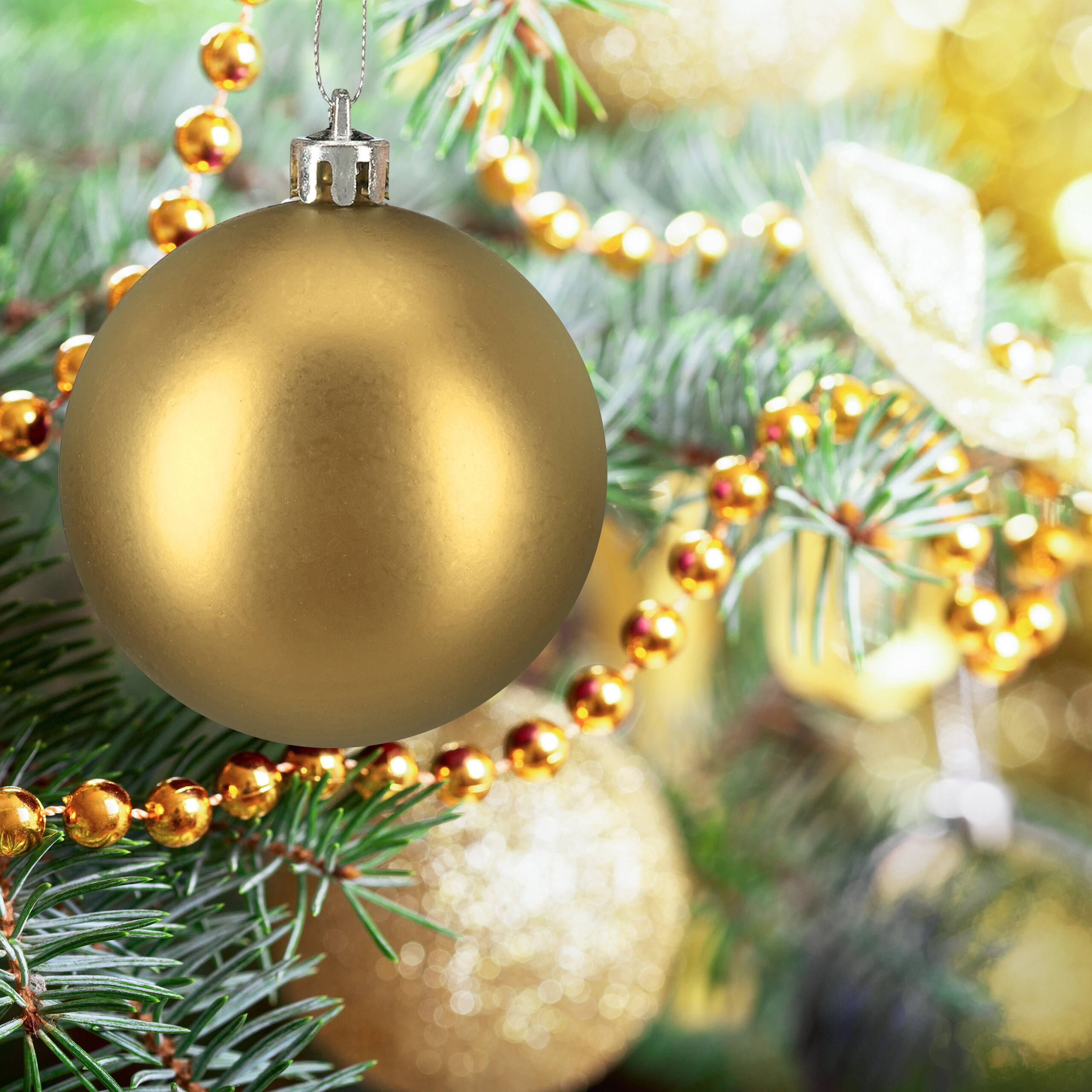 Eine matte goldene Weihnachtskugel hängt an einem Weihnachtsbaum mit goldenen Perlenketten.