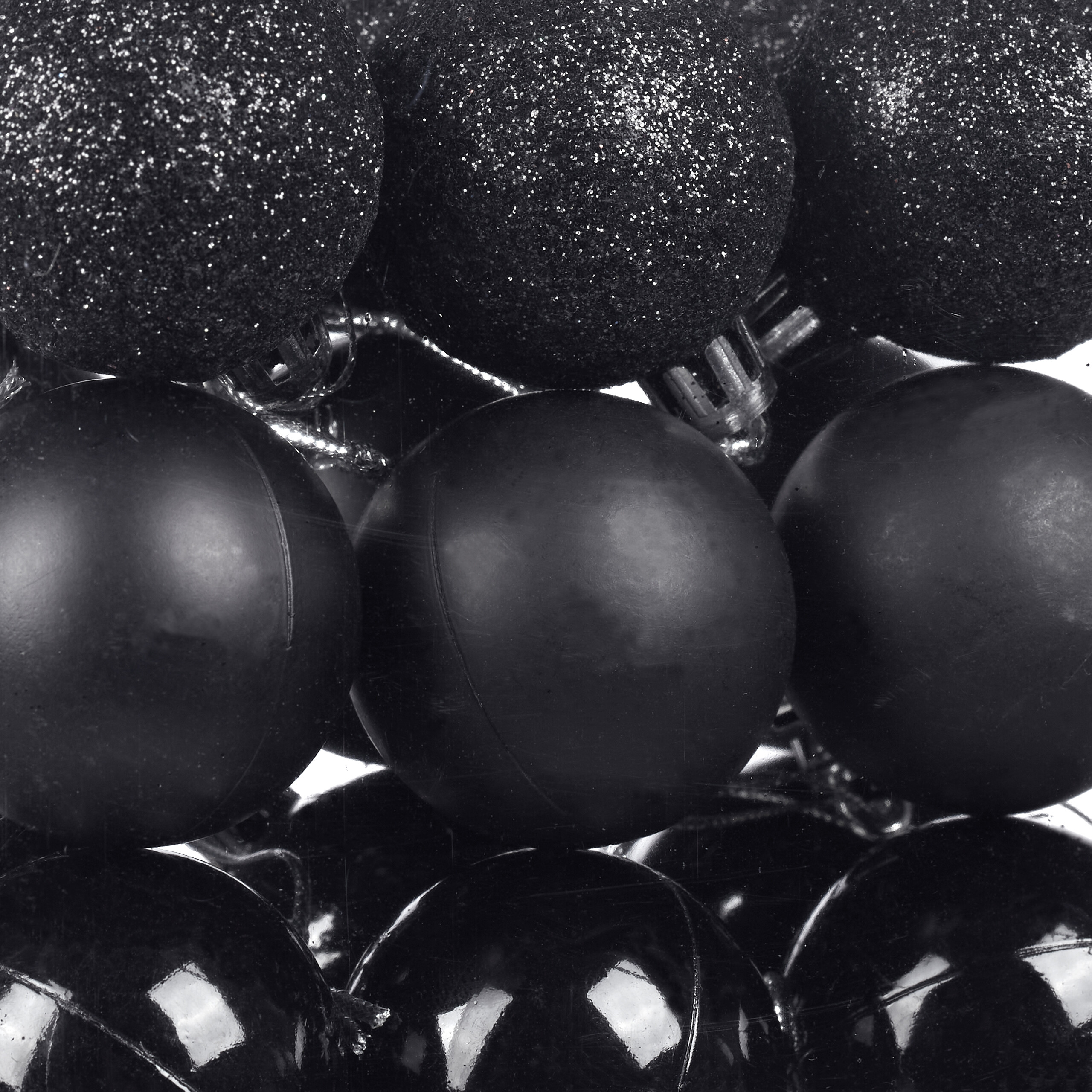 Glänzende, matte und glitzernde schwarze Weihnachtskugeln eng gestapelt.