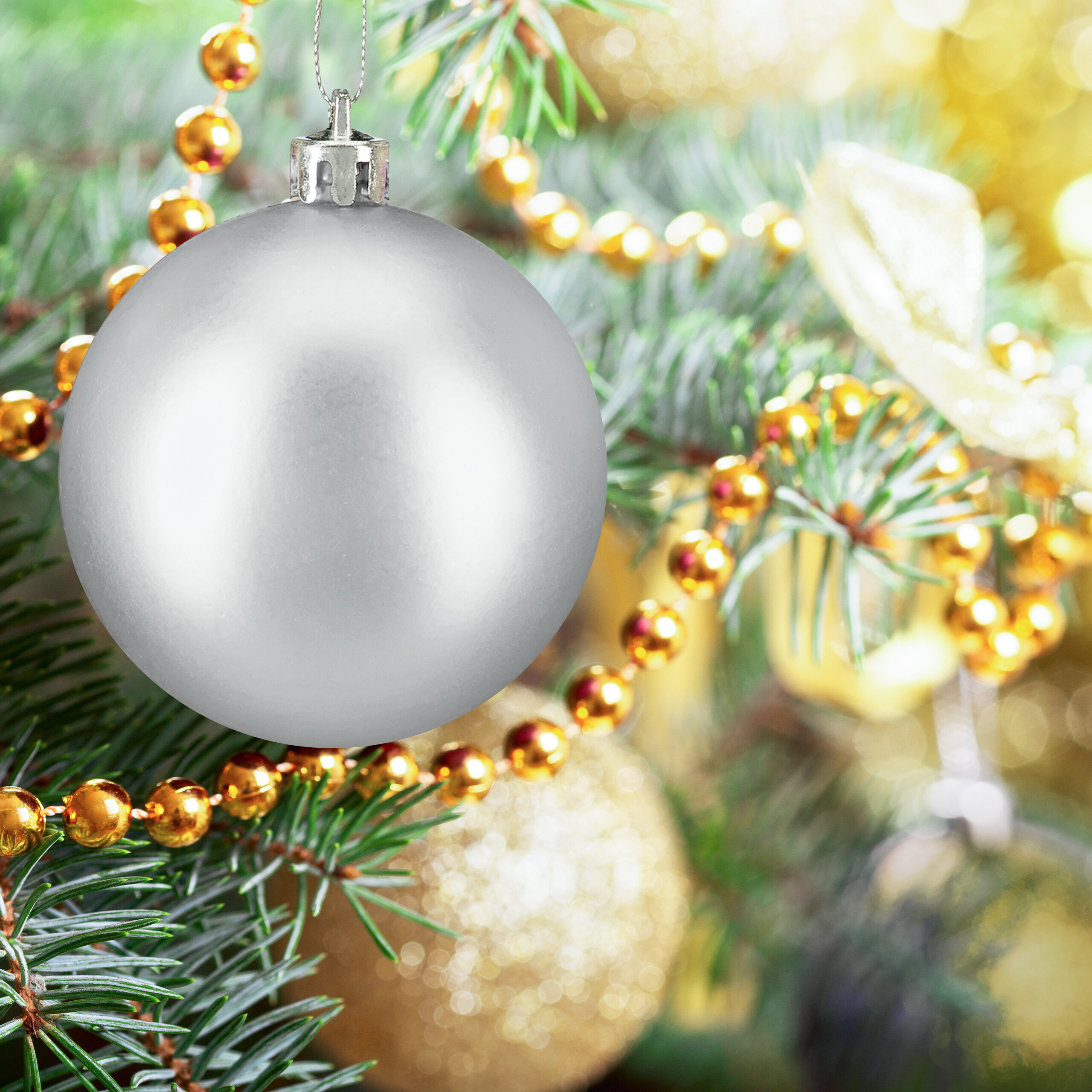 Eine matte silberne Weihnachtskugel hängt an einem grünen Baum, umgeben von goldenen Perlenketten.