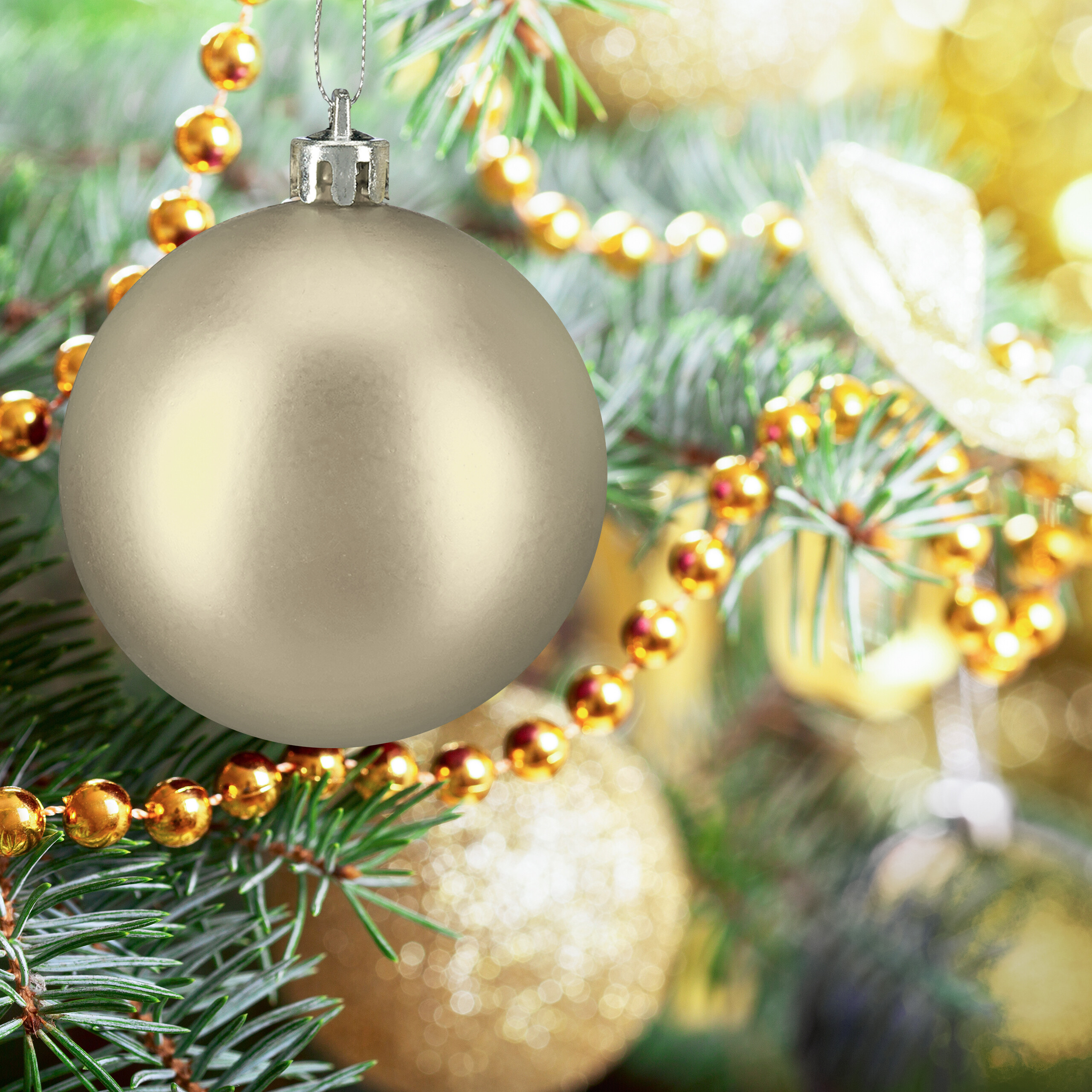 Eine glänzende silberne Weihnachtskugel hängt an einem grünen Ast, umgeben von goldenen Perlen.