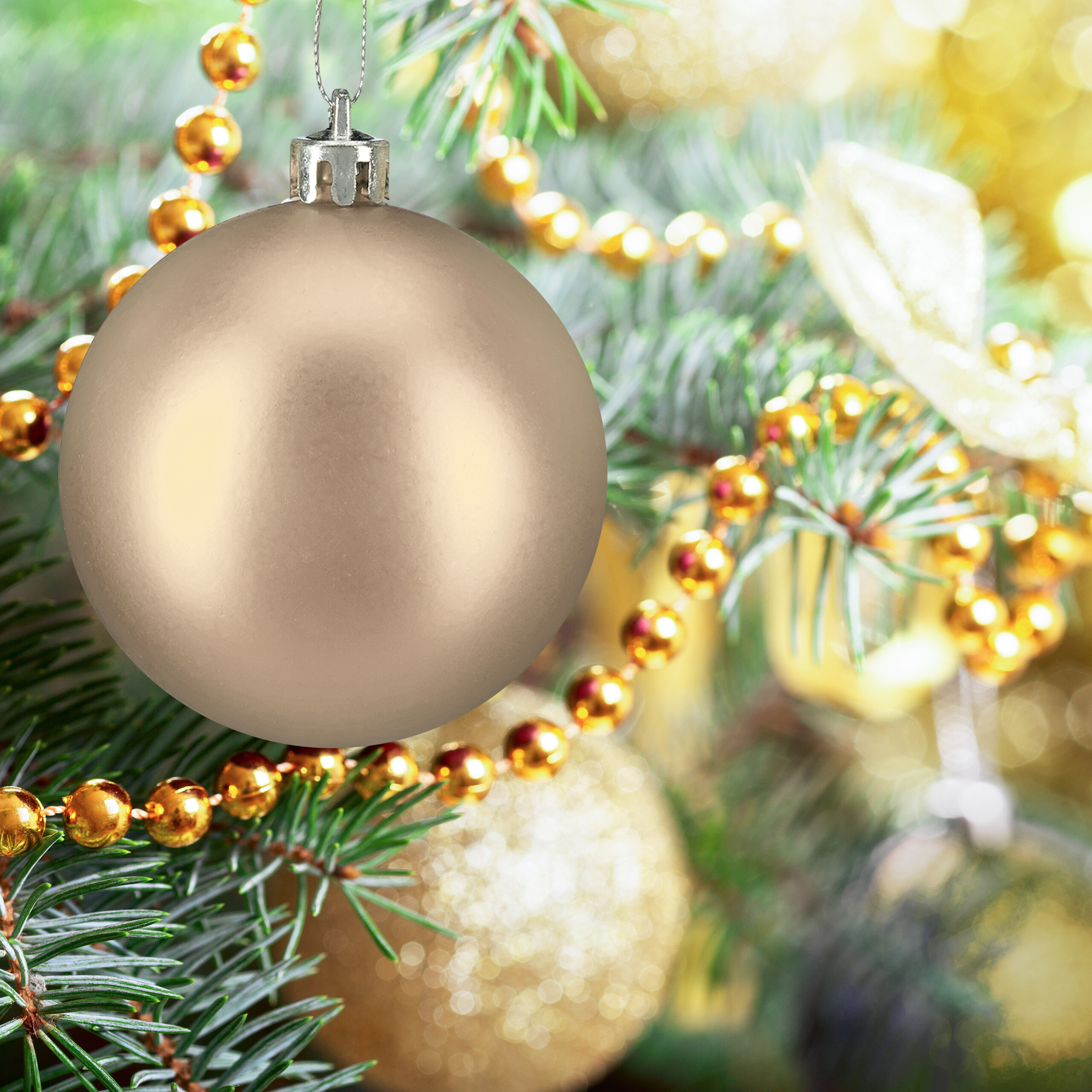 Eine matte goldene Weihnachtskugel hängt an einem grünen Weihnachtsbaum mit goldenen Perlenketten und funkelndem Hintergrund.