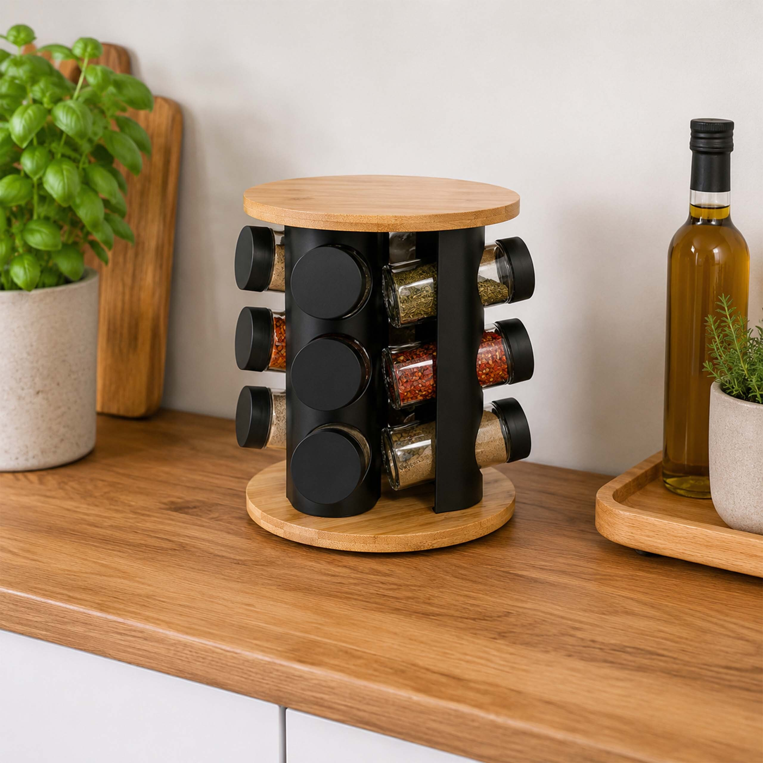 Ein drehbares Gewürzregal mit Holz und schwarzen Gläsern steht auf einer Holzarbeitsplatte, flankiert von Pflanzen und Öl.