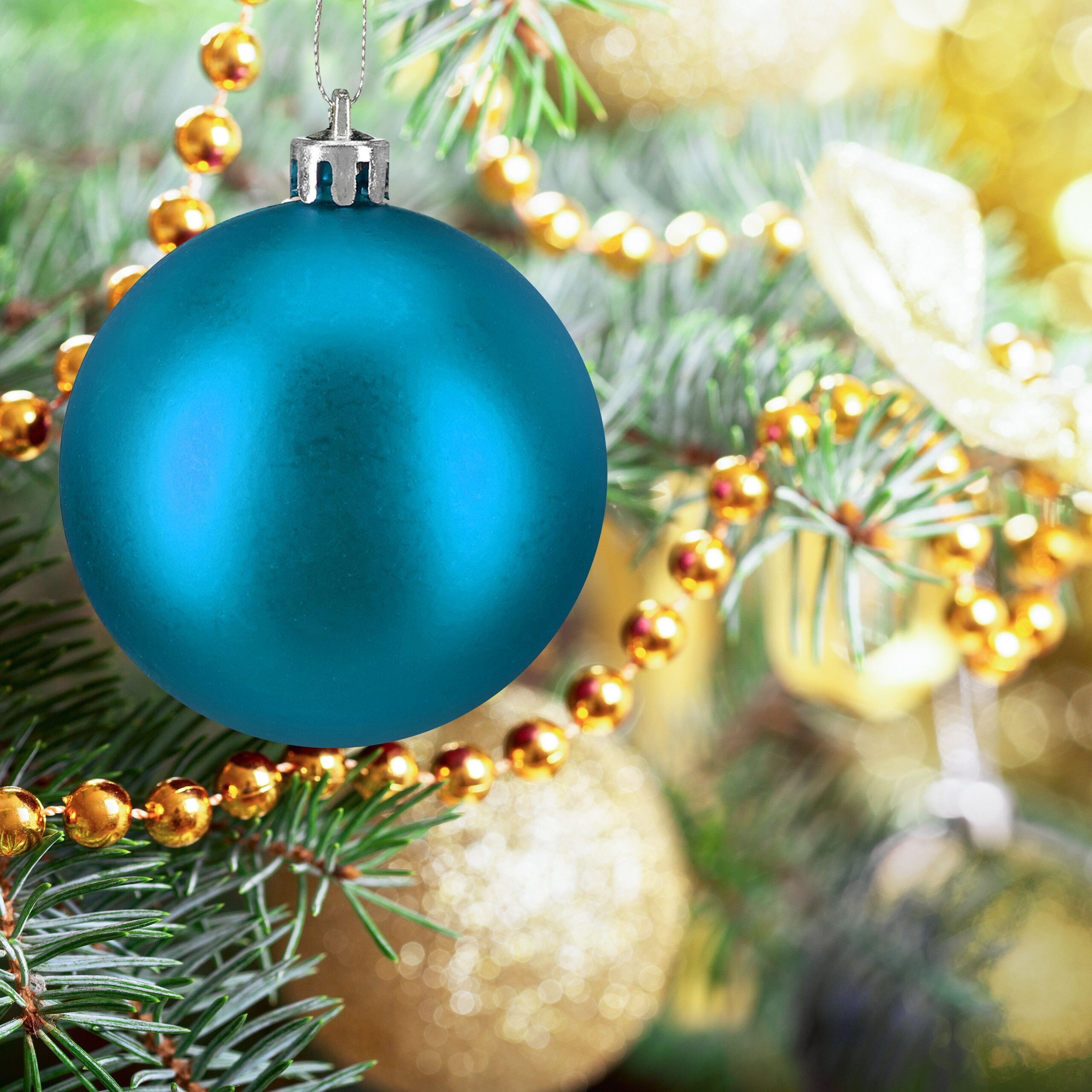 Eine glänzende blaue Weihnachtskugel hängt an einem Tannenbaum, umgeben von goldenen Perlenketten.