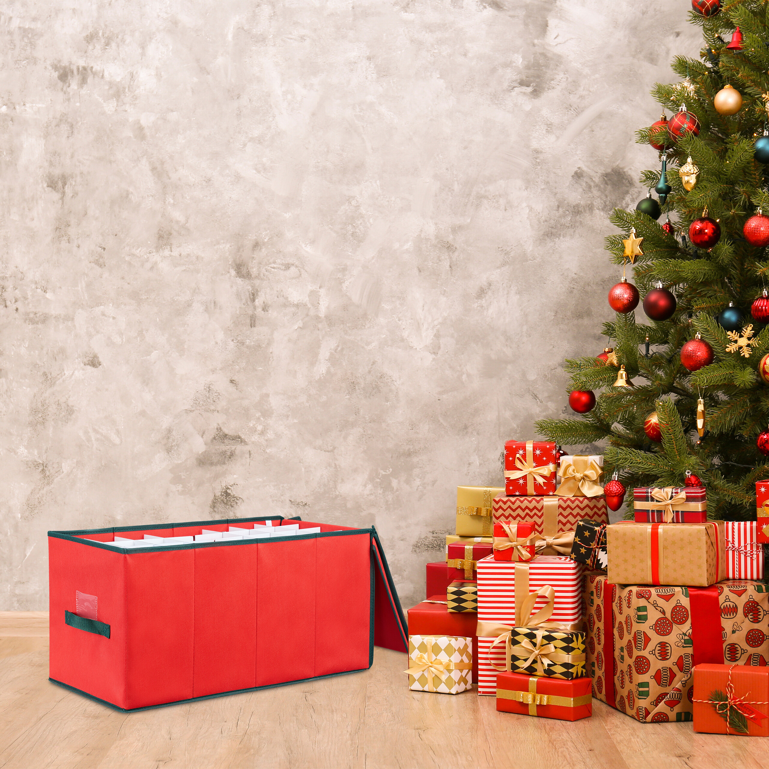 Ein geschmückter Weihnachtsbaum mit vielen Geschenken darunter und eine rote Aufbewahrungsbox auf dem Holzfußboden.