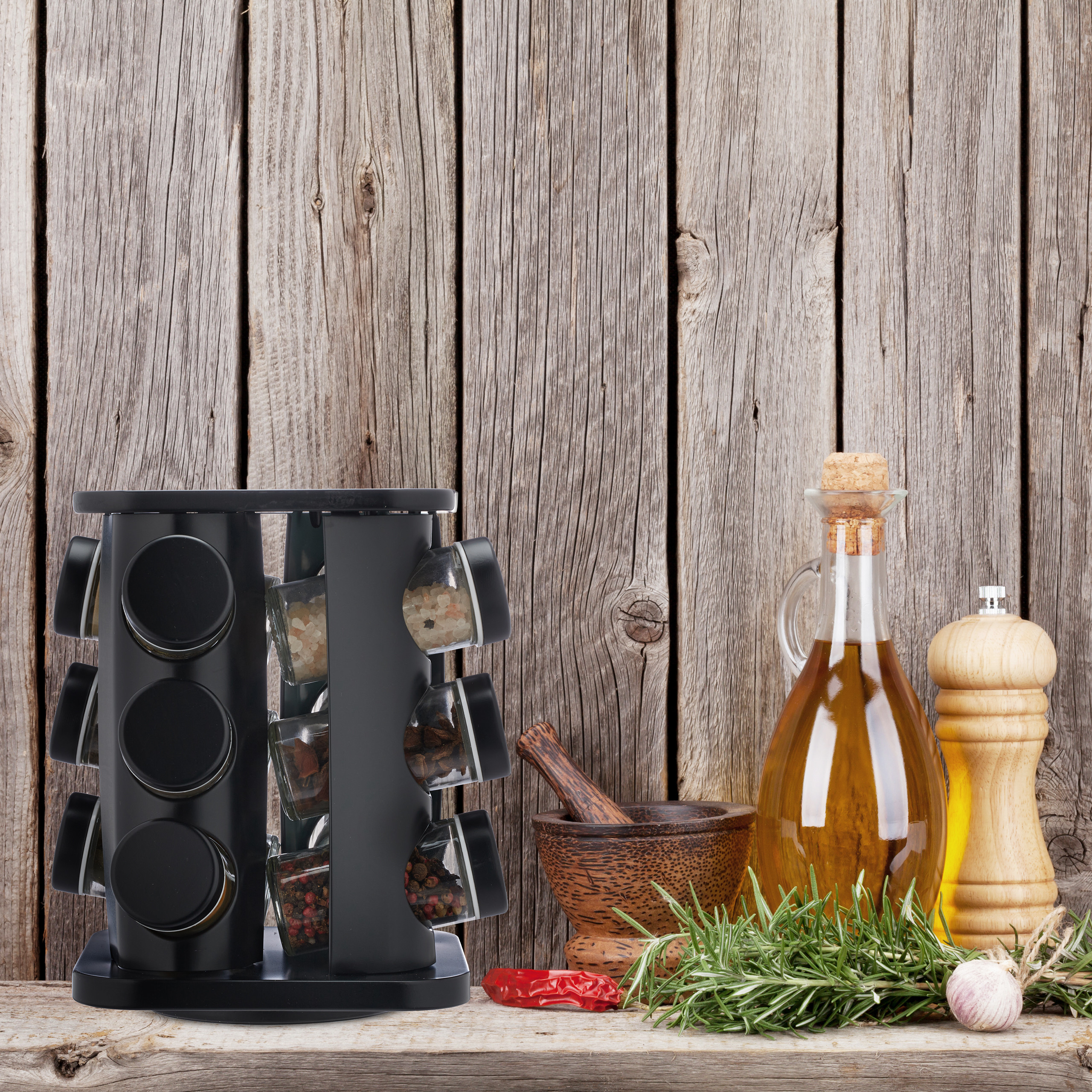 Gewürzregal, Ölflasche, Holzmörser, Rosmarin und Pfeffermühle vor Holzwand.