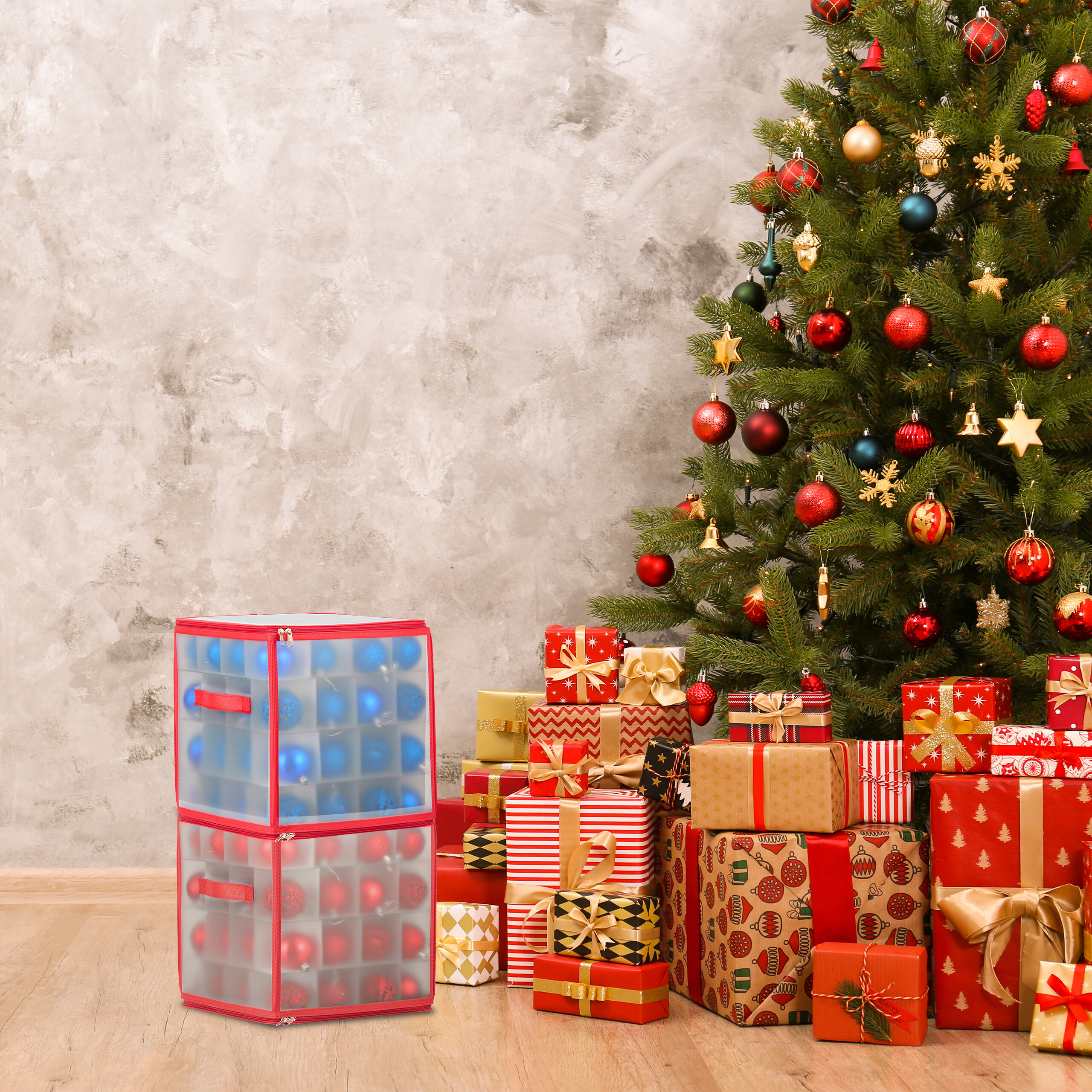 Ein geschmückter Weihnachtsbaum mit Geschenken und zwei transparenten Kisten voller Christbaumkugeln daneben.