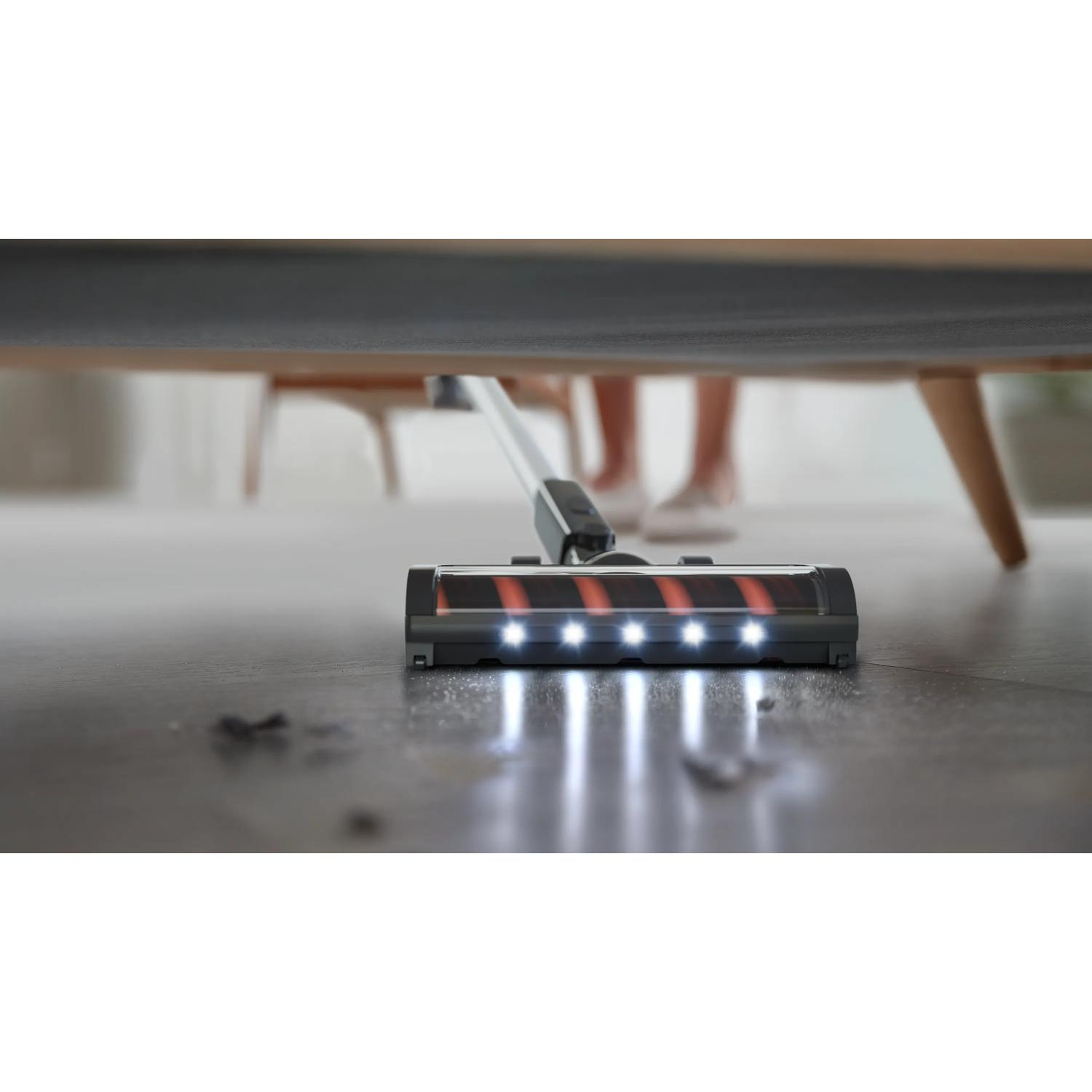 LED-es porszívó tisztítja a padlót egy ágy alatt.