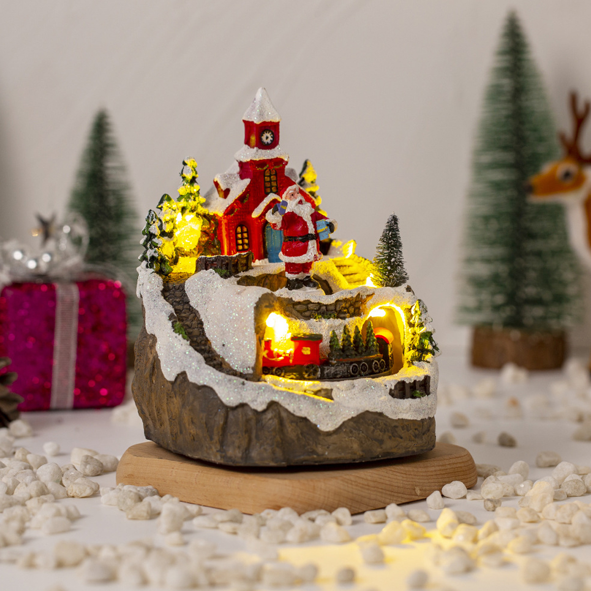 Beleuchtete Weihnachtsdorf-Skulptur auf Holzsockel mit Kirche, Weihnachtsmann und Zug.