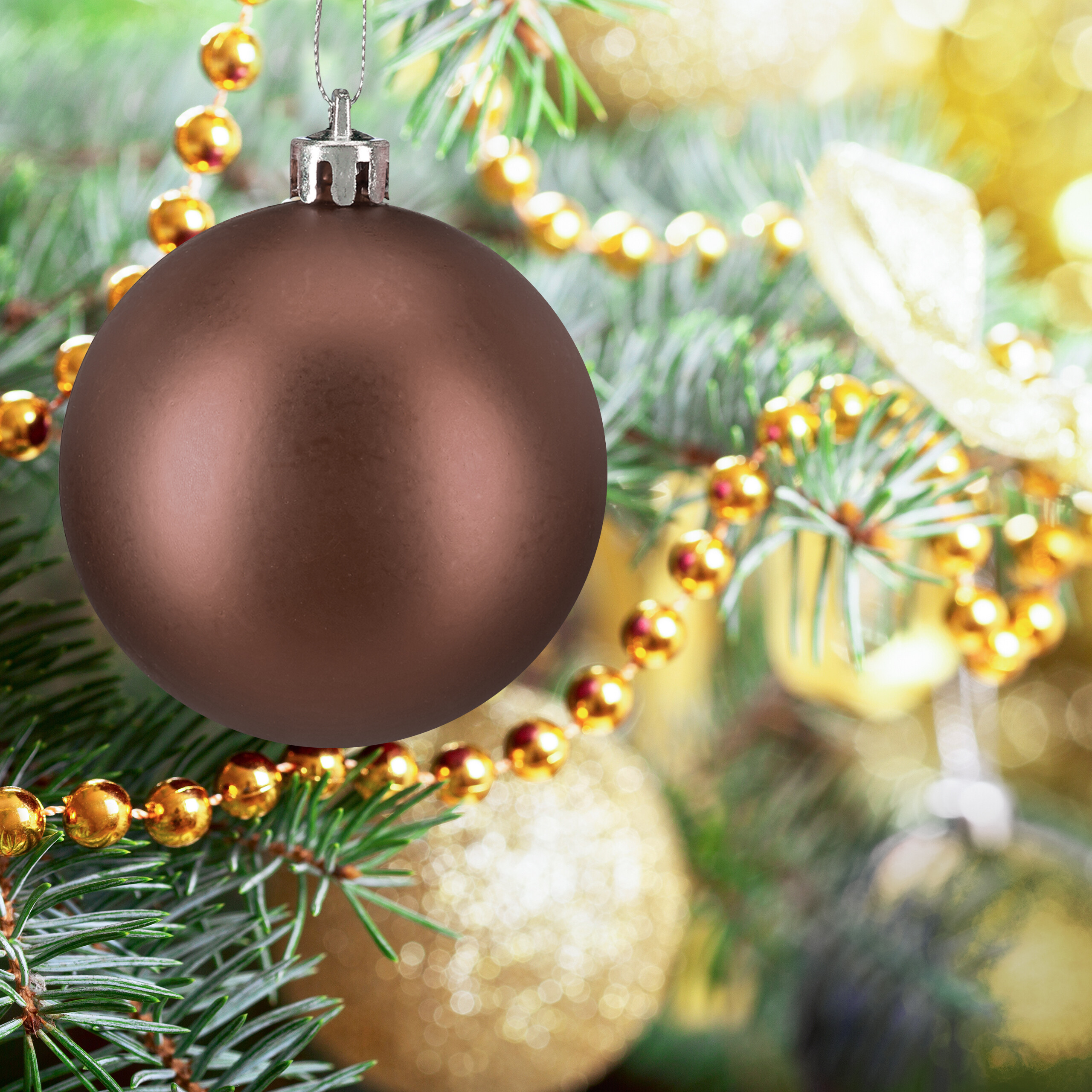 Eine matte braune Weihnachtskugel hängt an einem Tannenbaum, umgeben von goldenen Perlenketten und Lichtern.