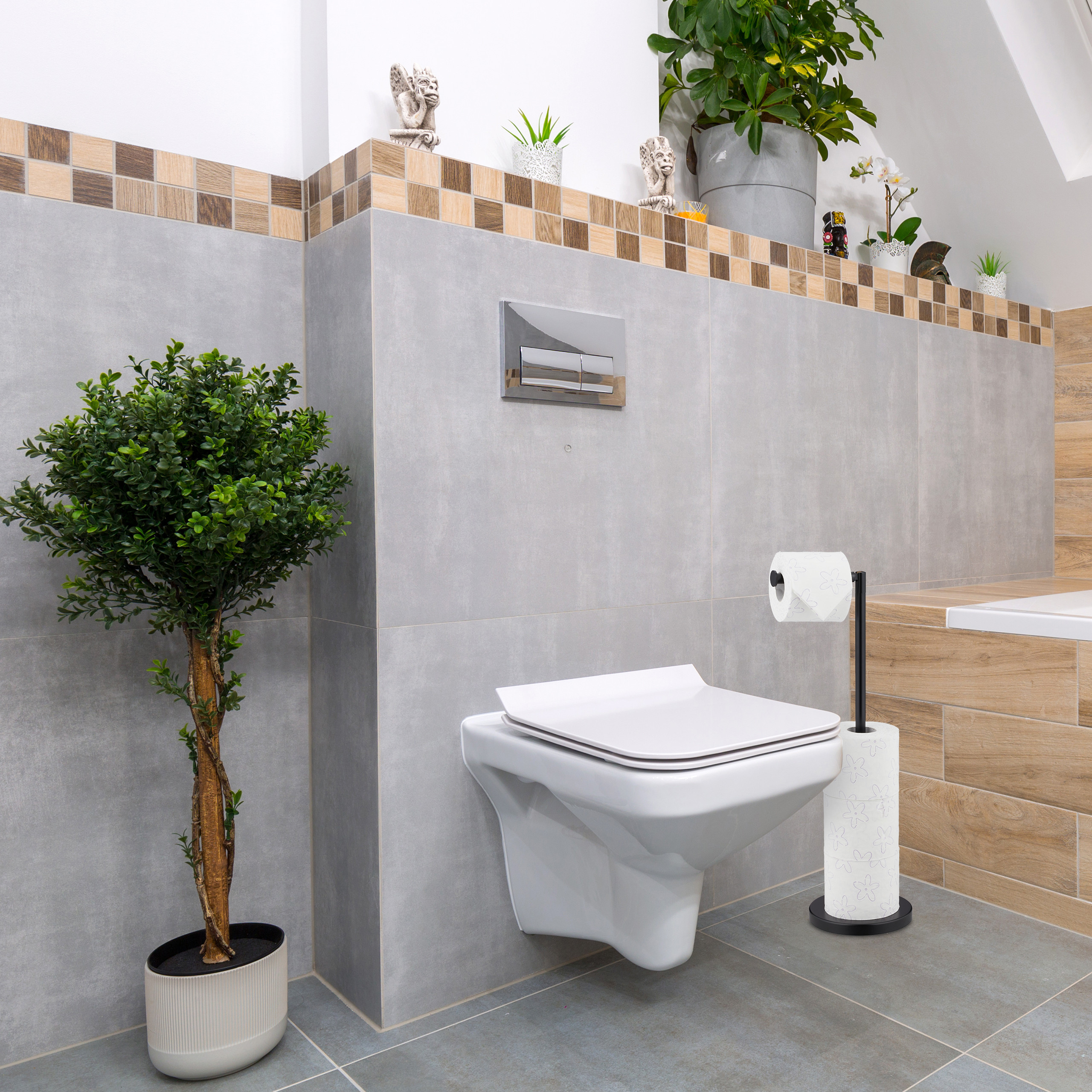 Moderne weiße Toilette an grauer gefliester Wand mit Grünpflanzen und Toilettenpapierhalter.