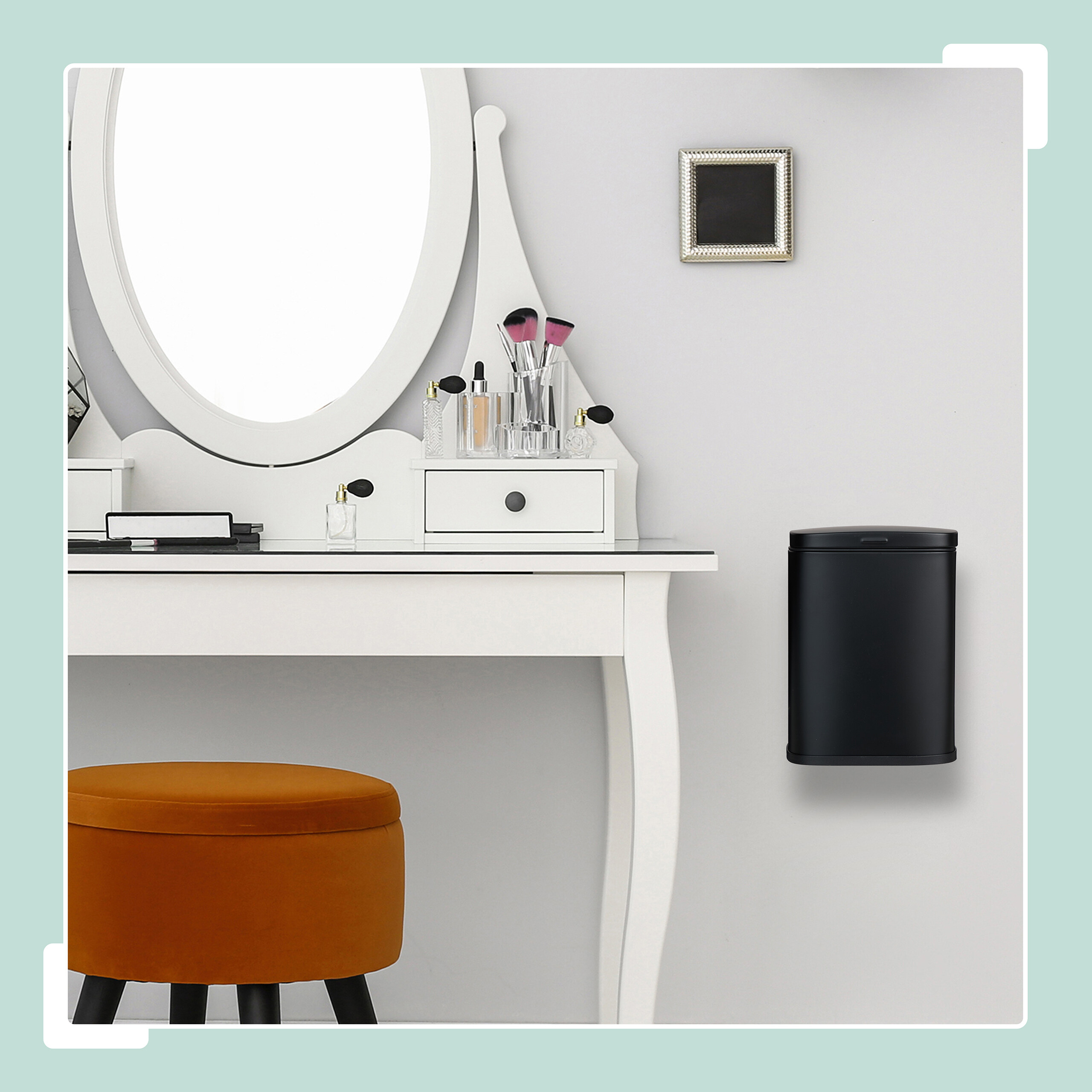 Ein weißer Schminktisch mit ovalem Spiegel, Make-up, orangefarbenem Hocker und schwarzem Eimer.
