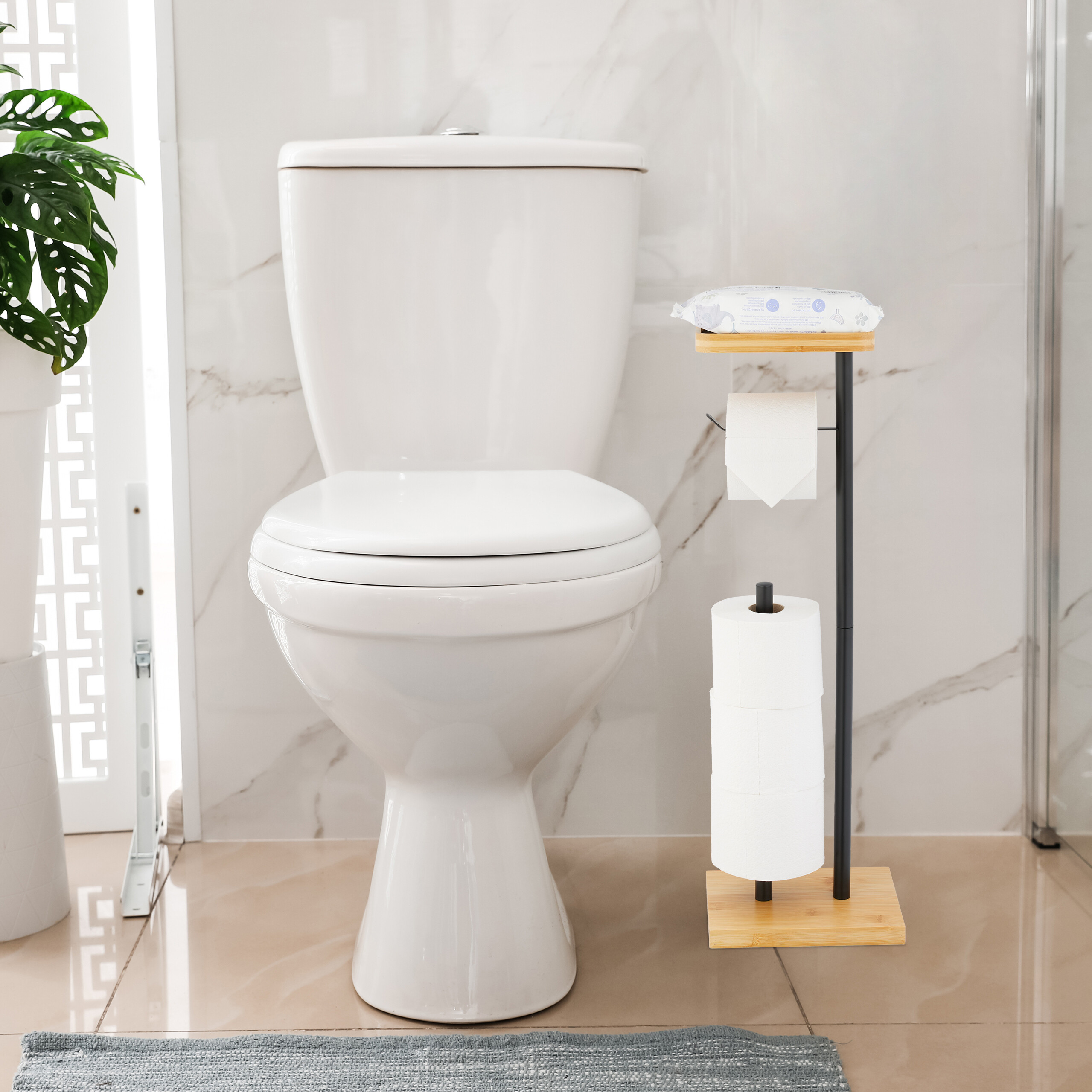 Eine weiße Toilette steht in einem Bad mit Marmorwänden, daneben ein Toilettenpapierhalter mit Holz- und Metallelementen.