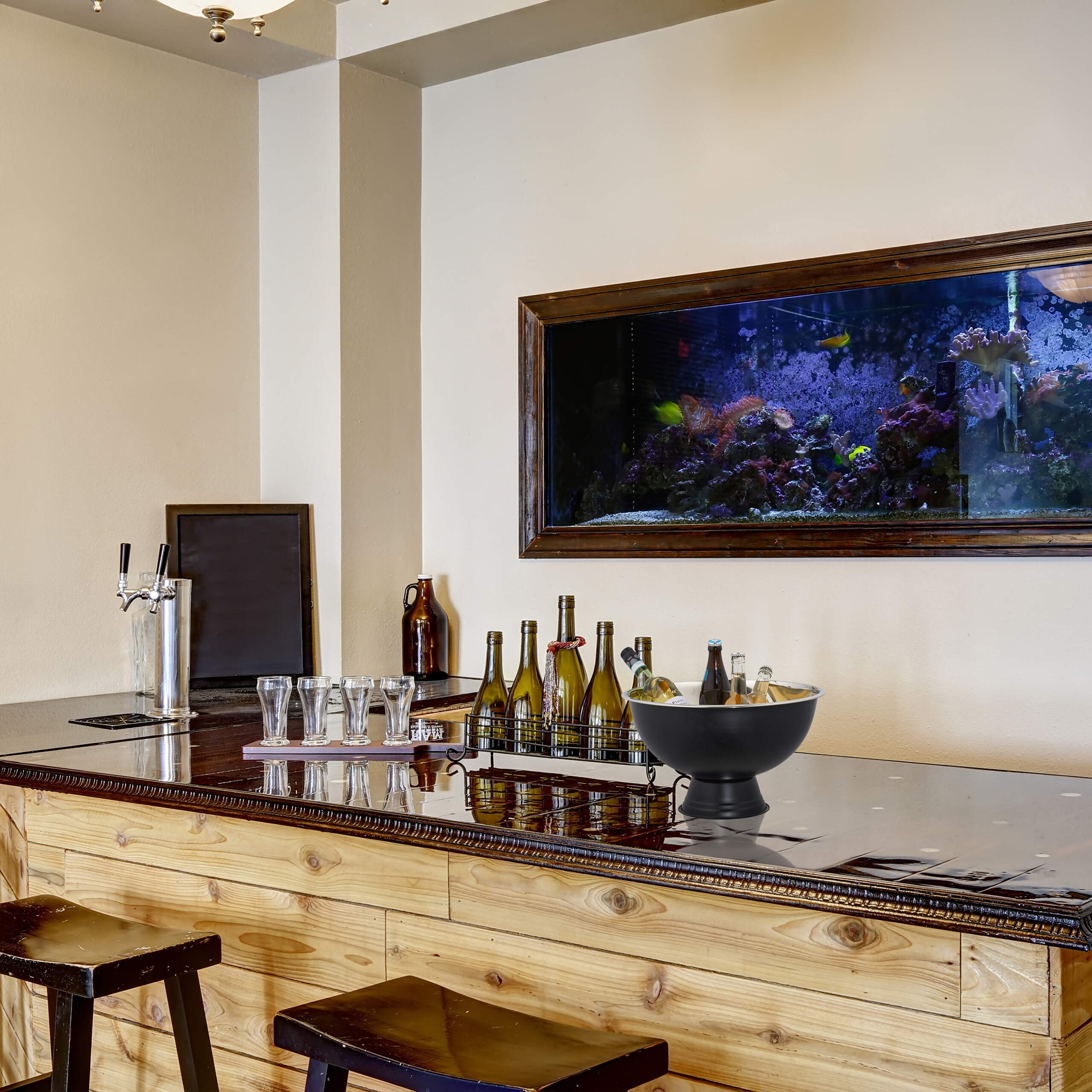 Eine hölzerne Bar mit Bierhahn, Gläsern, Flaschen im Halter, Flaschenkühler und einem großen Aquarium an der Wand.