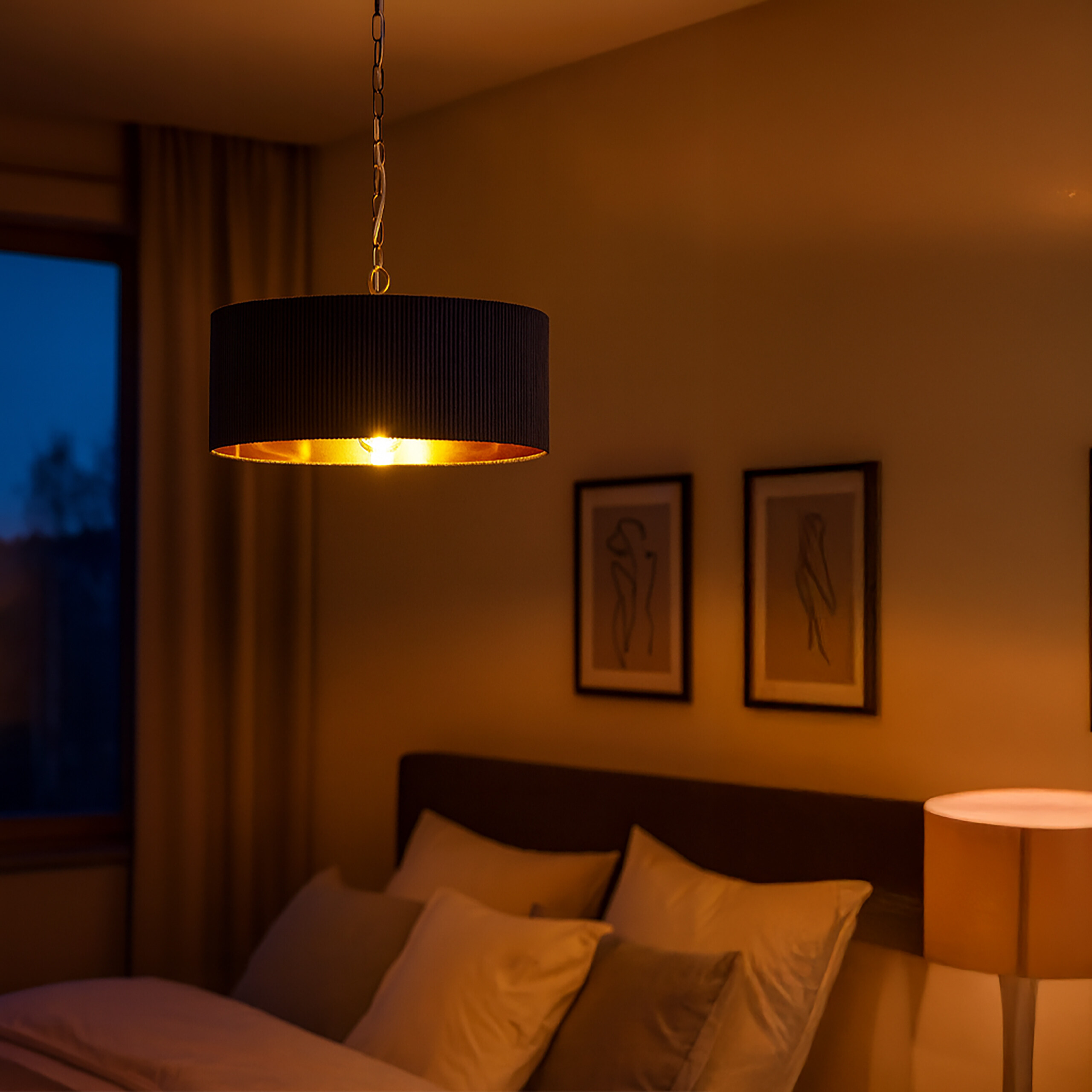 Gemütliches Schlafzimmer mit warmer Pendelleuchte, gerahmten Bildern an der Wand und einem beleuchteten Nachttisch.