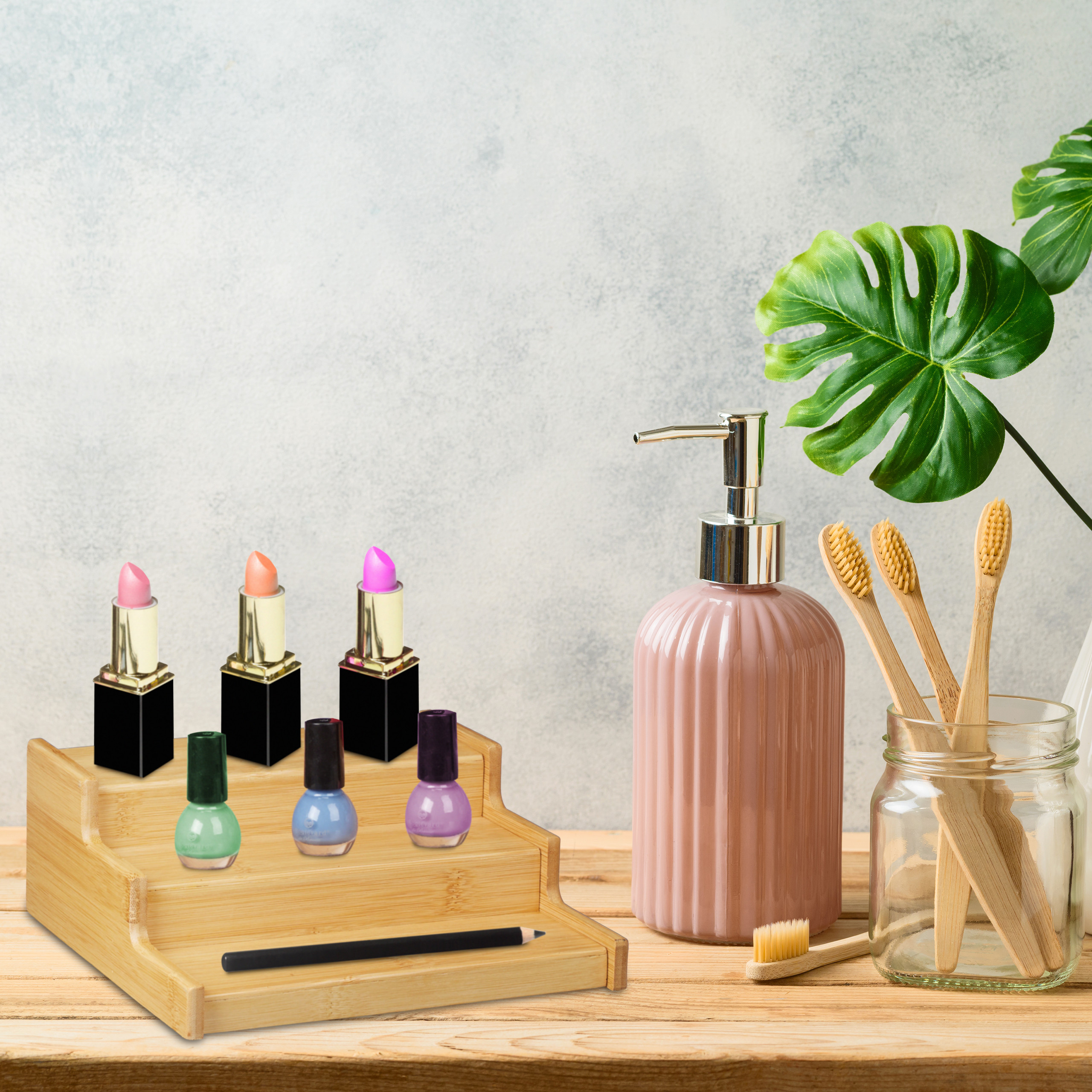 Ein Holzorganizer hält Lippenstifte und Nagellack neben Seifenspender, Zahnbürsten und Blättern.