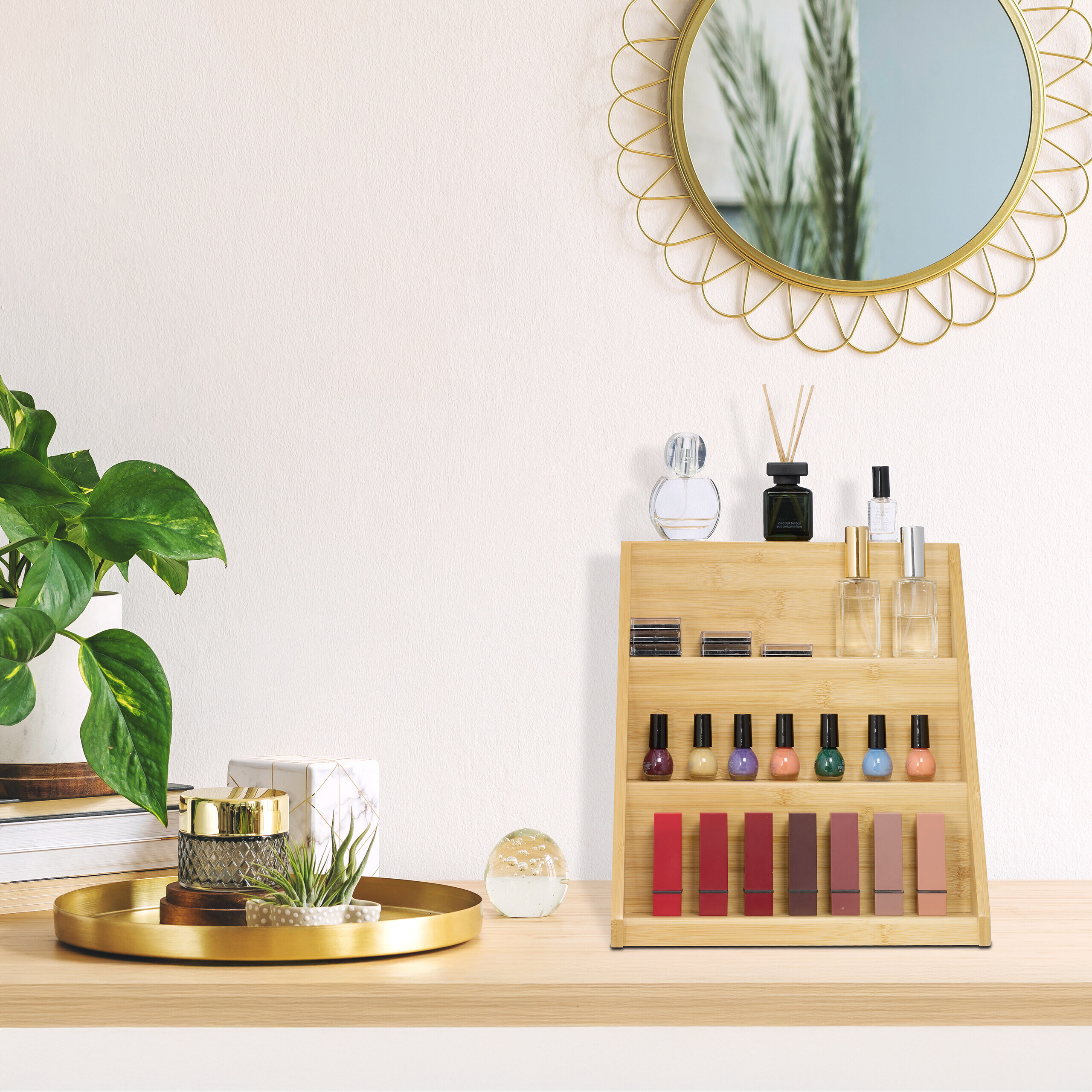 Ein Holzzusammenschluss auf einem Schreibtisch mit Kosmetik, Parfüm und Lippenstiften, daneben eine Pflanze und ein Spiegel.
