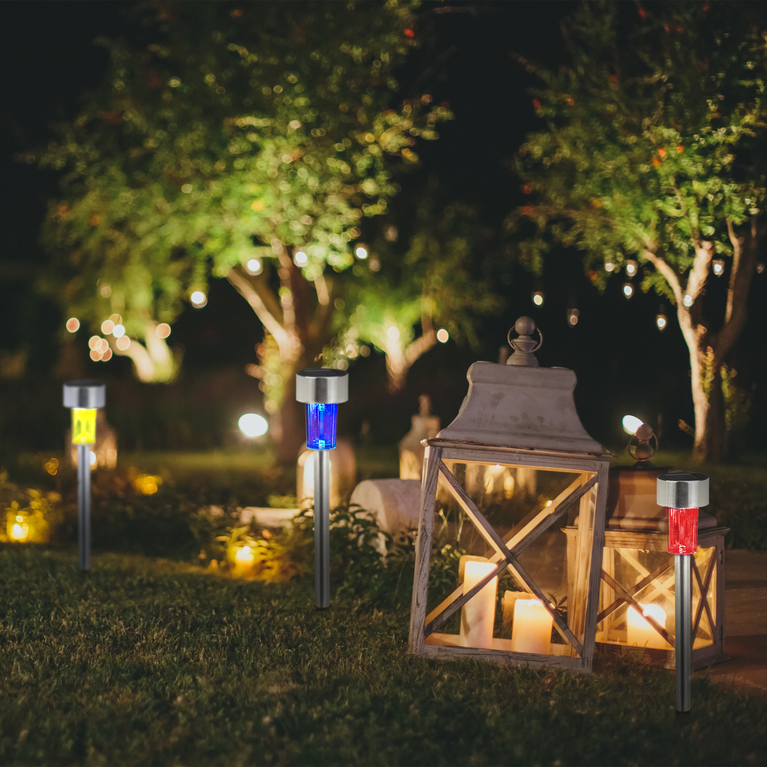 Solar-Gartenleuchten und Holzlaternen mit Kerzen leuchten in einem dunklen Garten.